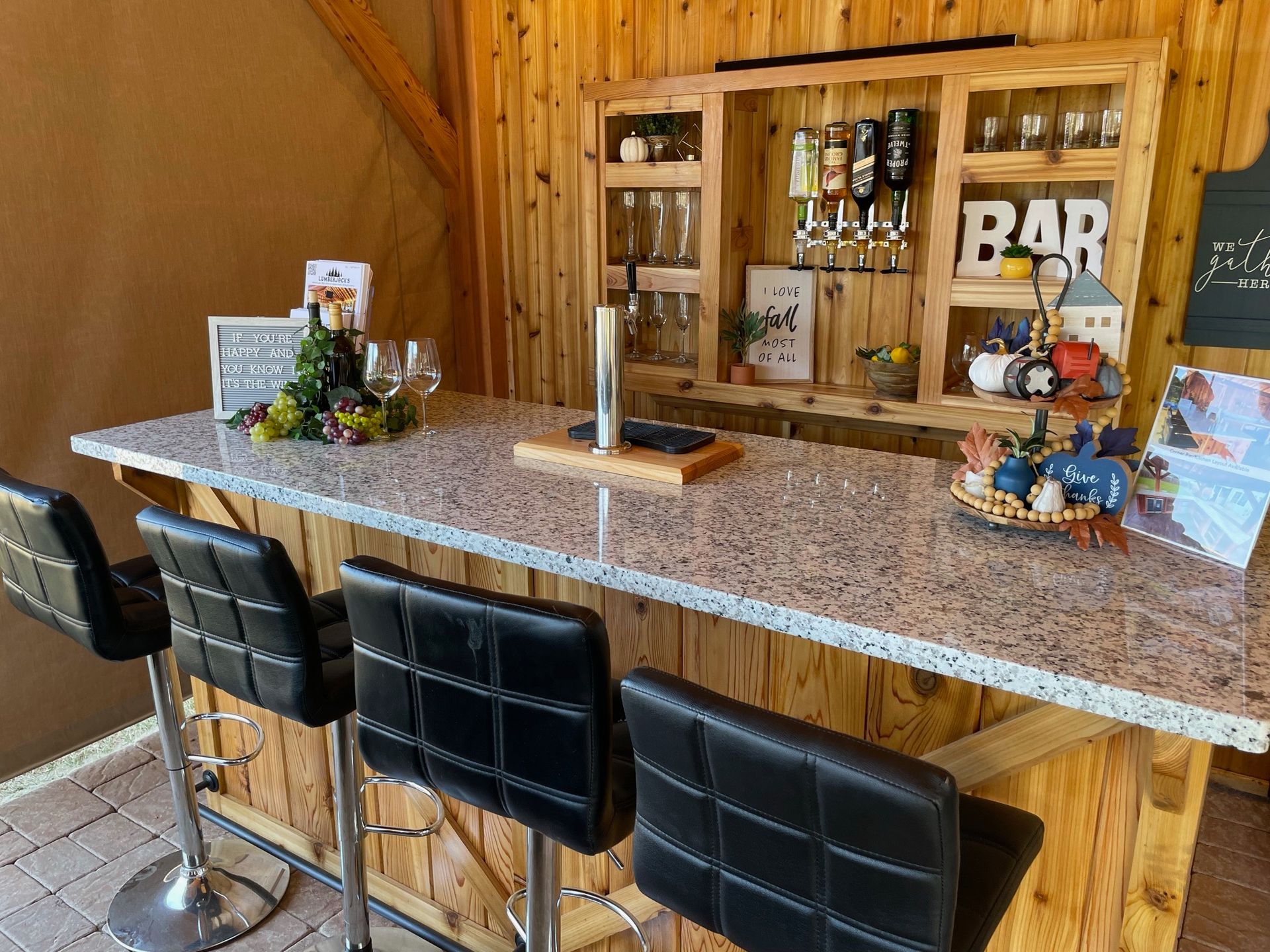 A wooden bar with a granite counter top and stools.