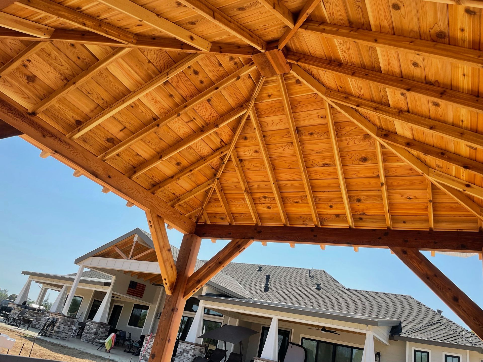 A wooden gazebo with a house in the background.