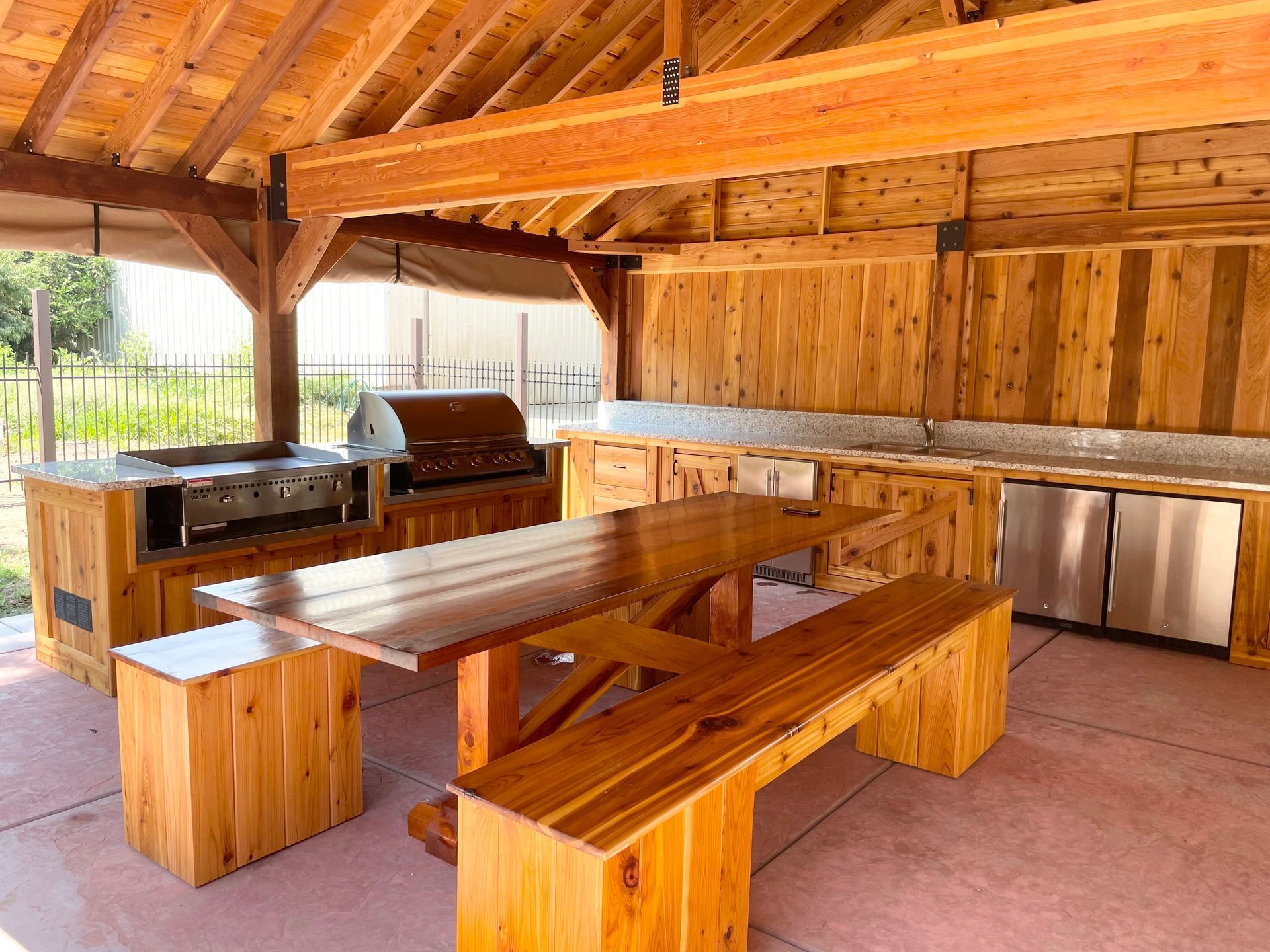 A wooden picnic table and benches under a wooden roof