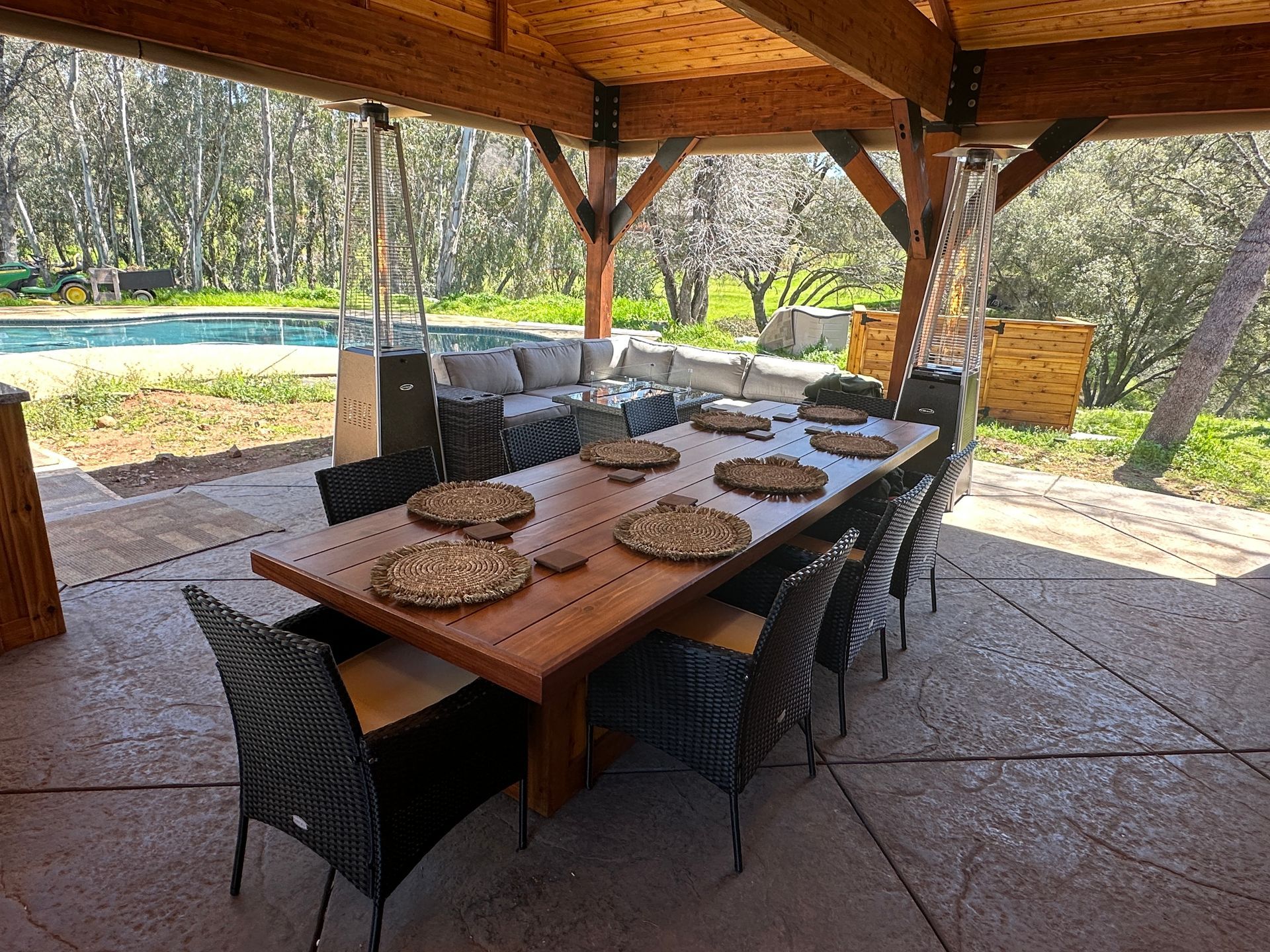 A large wooden table and chairs under a wooden roof.