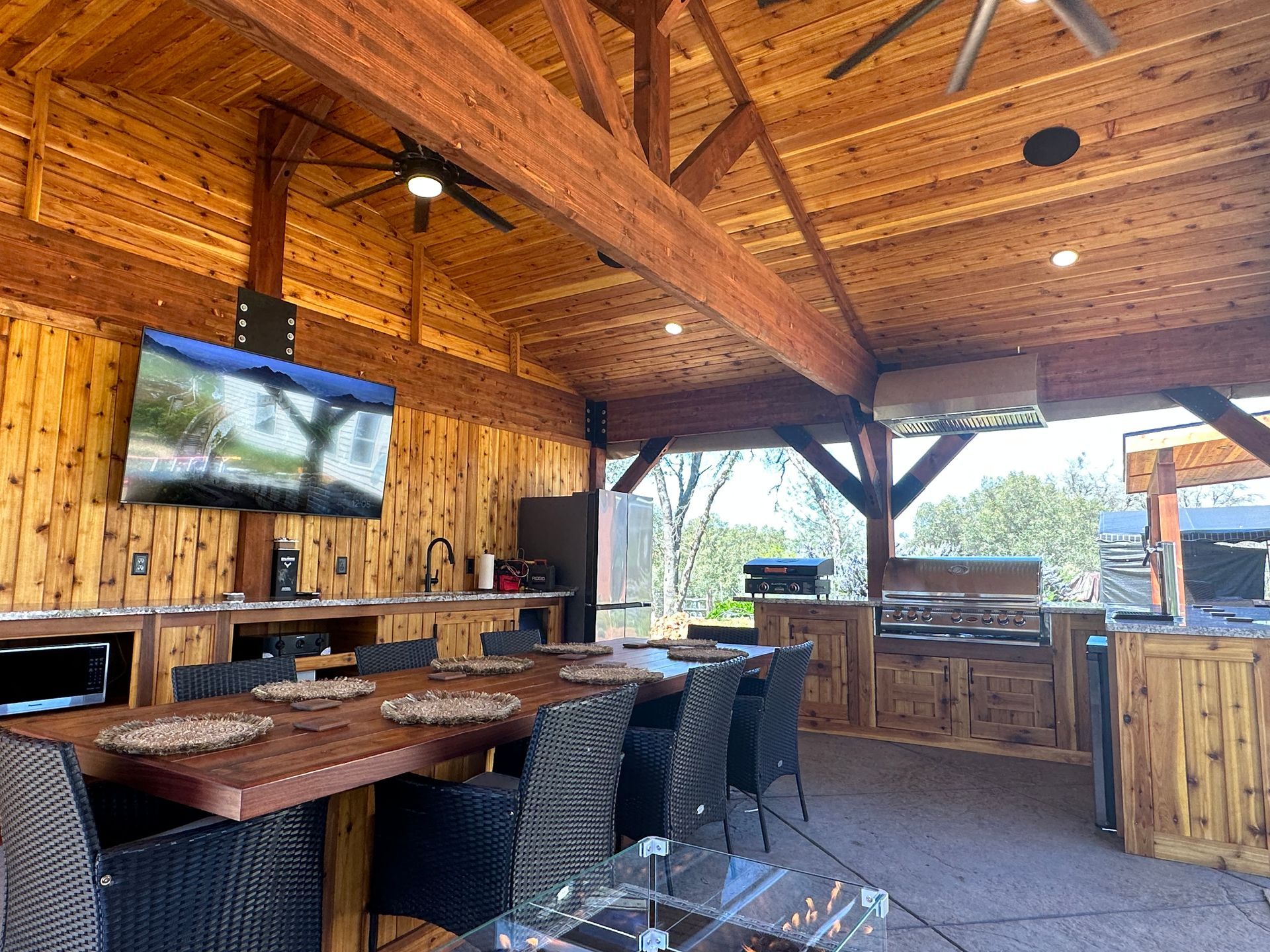 A dining room with a table and chairs and a television on the wall.