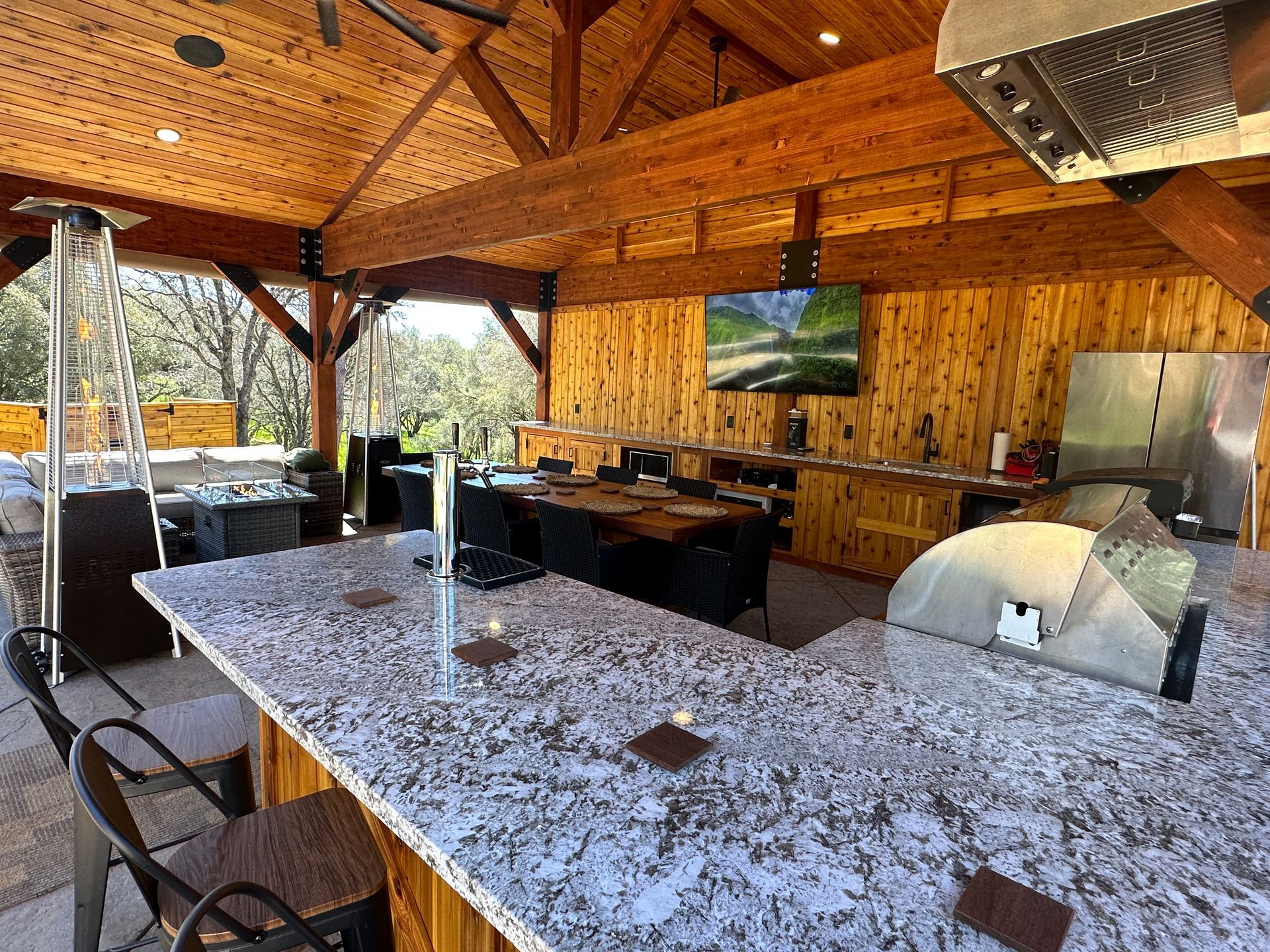 A large outdoor kitchen with granite counter tops and stainless steel appliances.