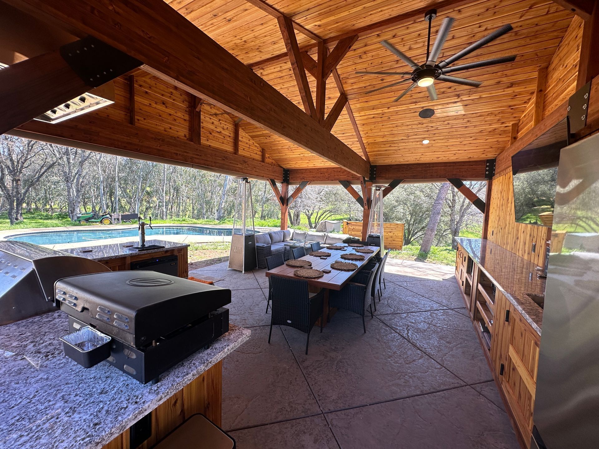 A large outdoor kitchen with a table and chairs and a ceiling fan.