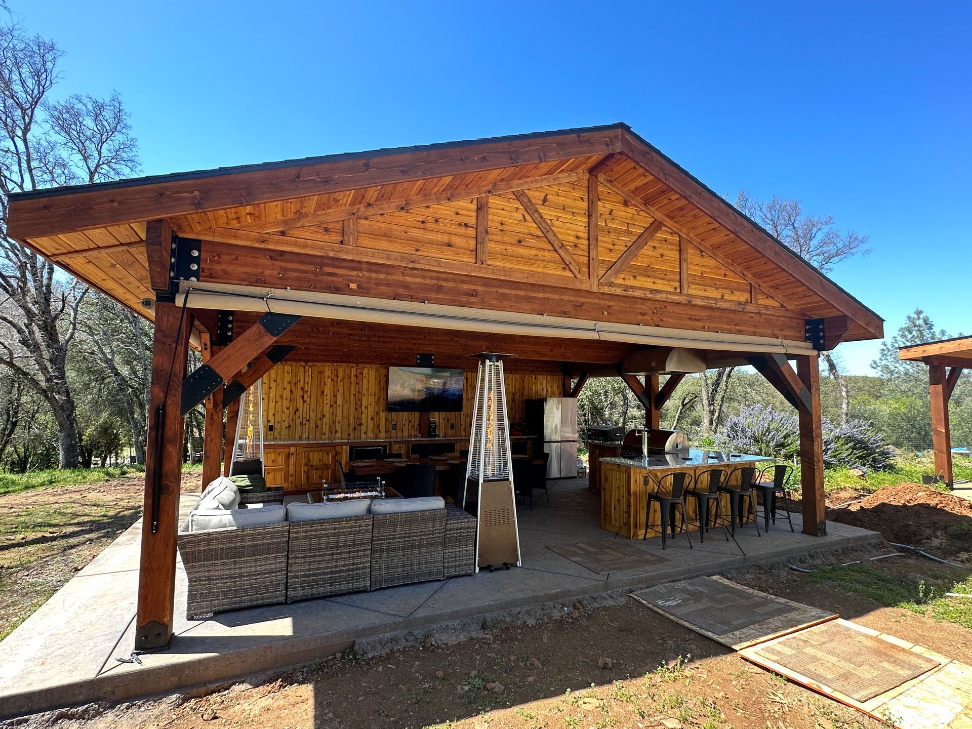 A large wooden pavilion with a kitchen and a patio area underneath it.