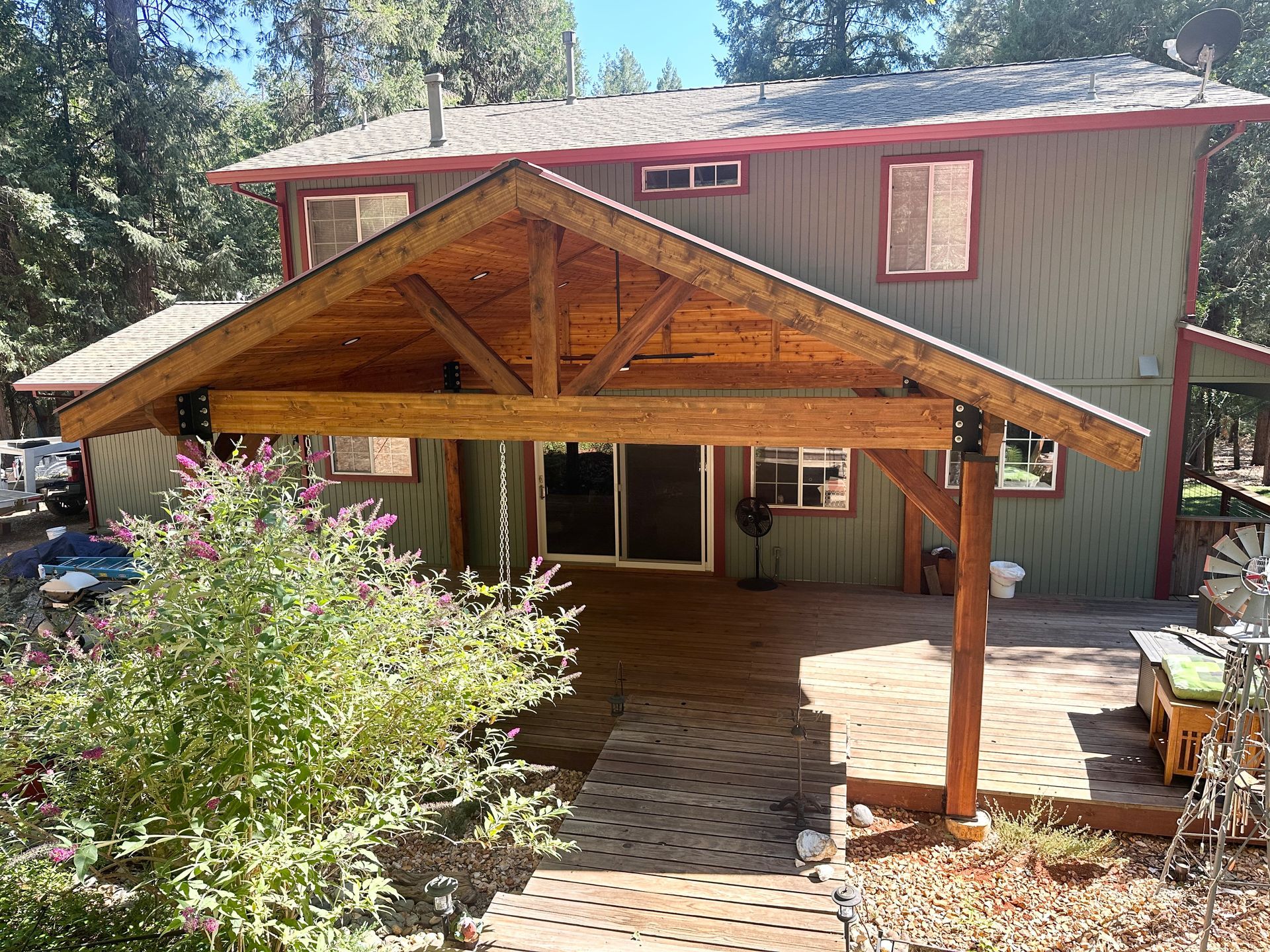 The back of a house with a wooden porch and a wooden deck.