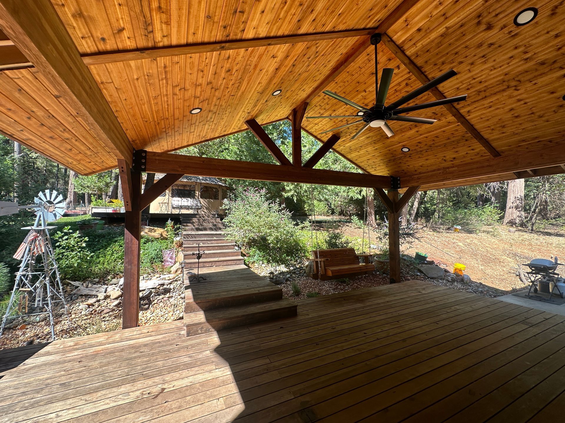 A wooden deck with a ceiling fan hanging from the ceiling.