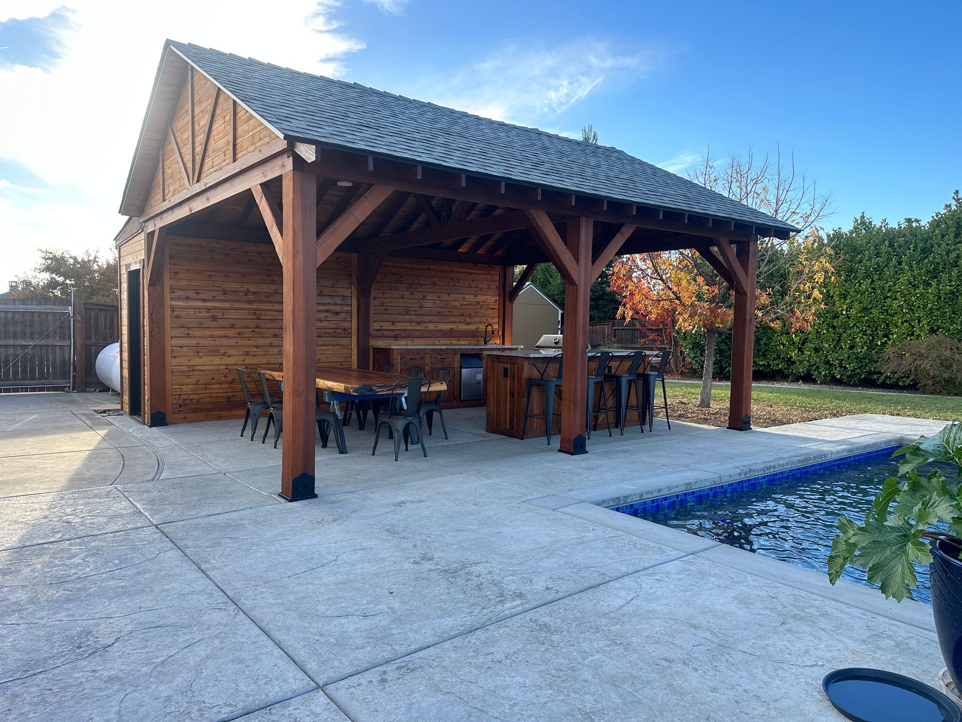 A wooden pavilion is sitting next to a swimming pool.