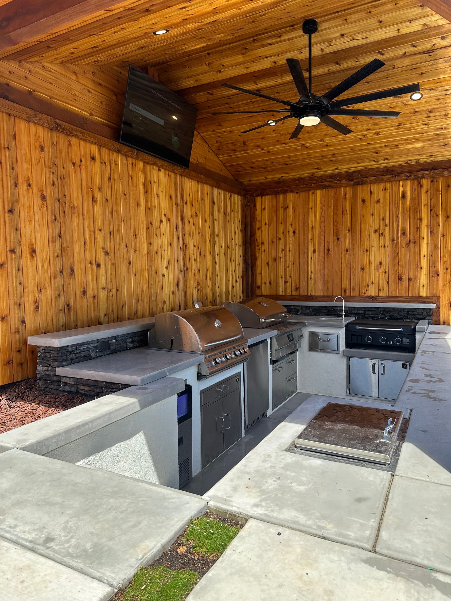 A large outdoor kitchen with a grill and a ceiling fan.
