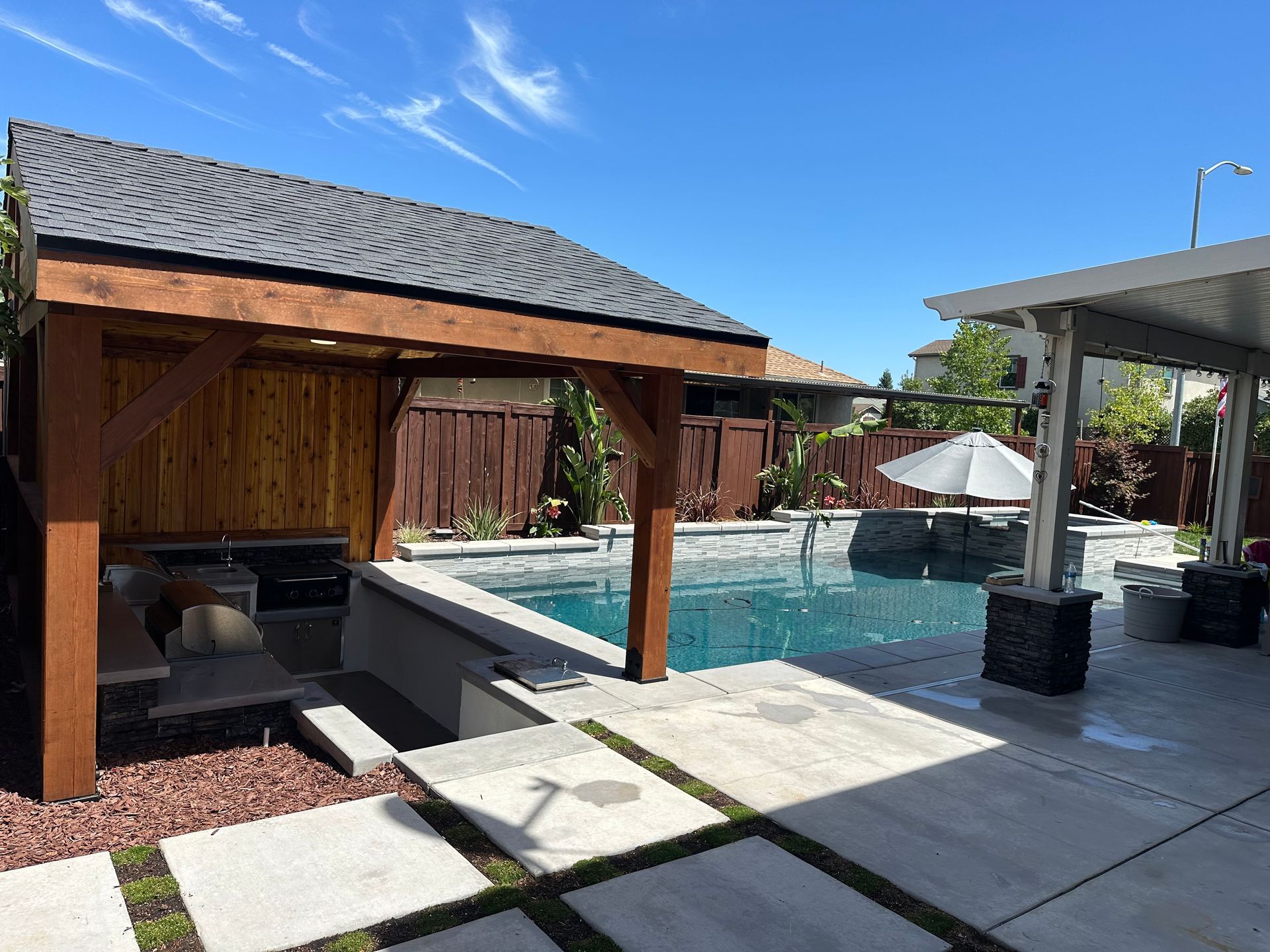 A large swimming pool with a wooden pavilion in the backyard.