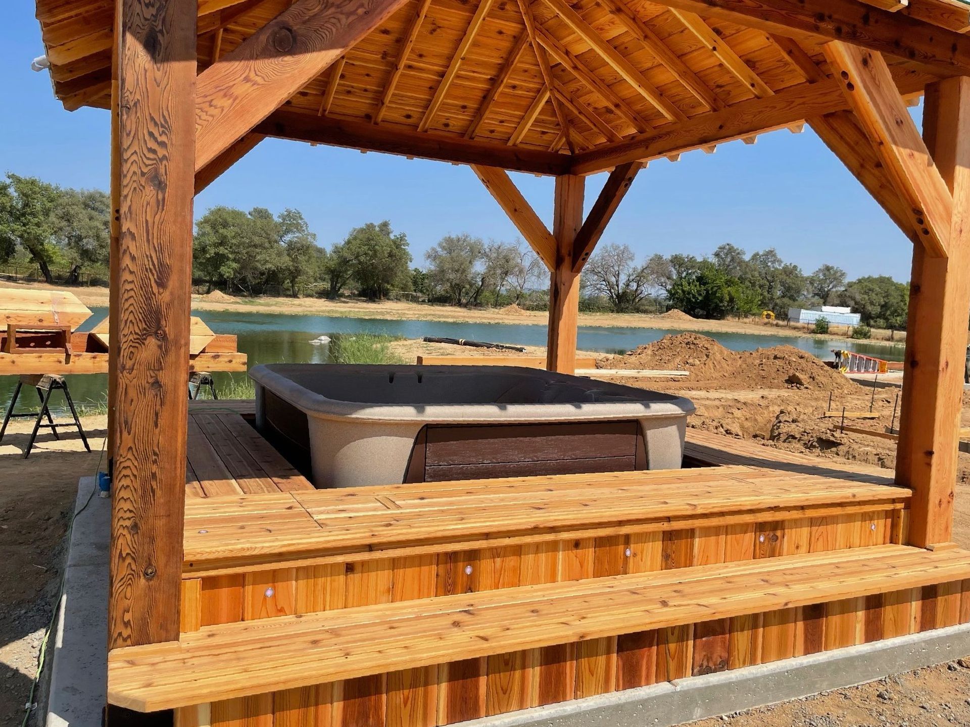 A wooden pavilion with a hot tub inside of it