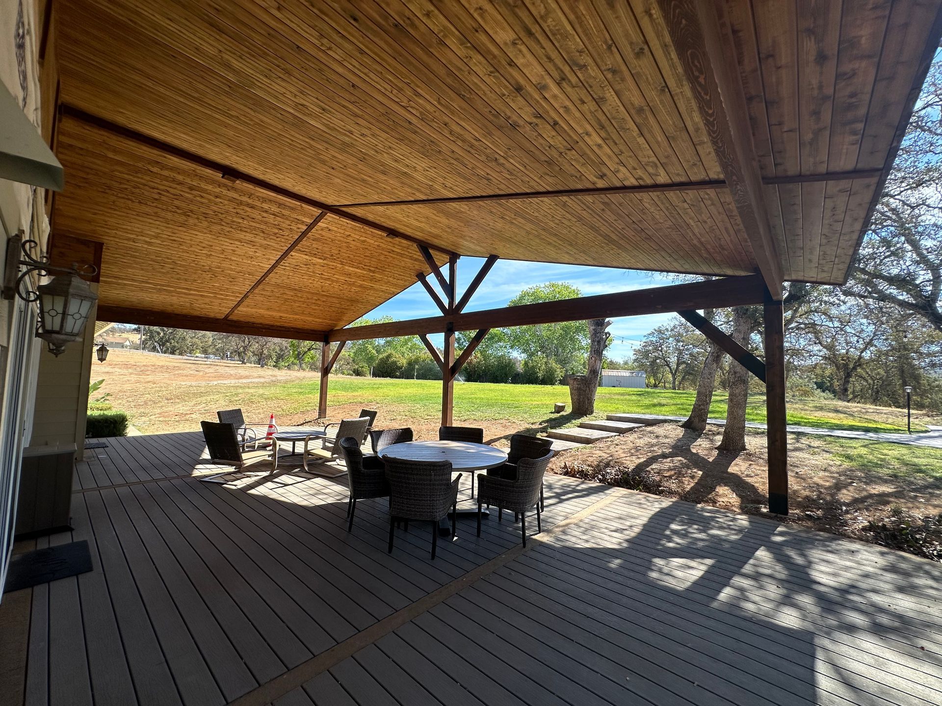 A wooden deck with a table and chairs under a canopy.