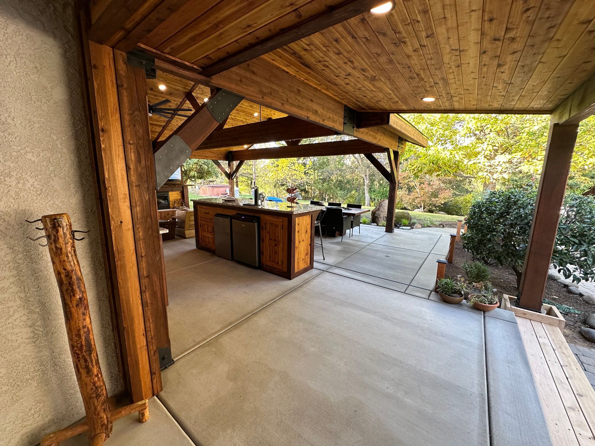 A large covered patio with a wooden ceiling and a kitchen.