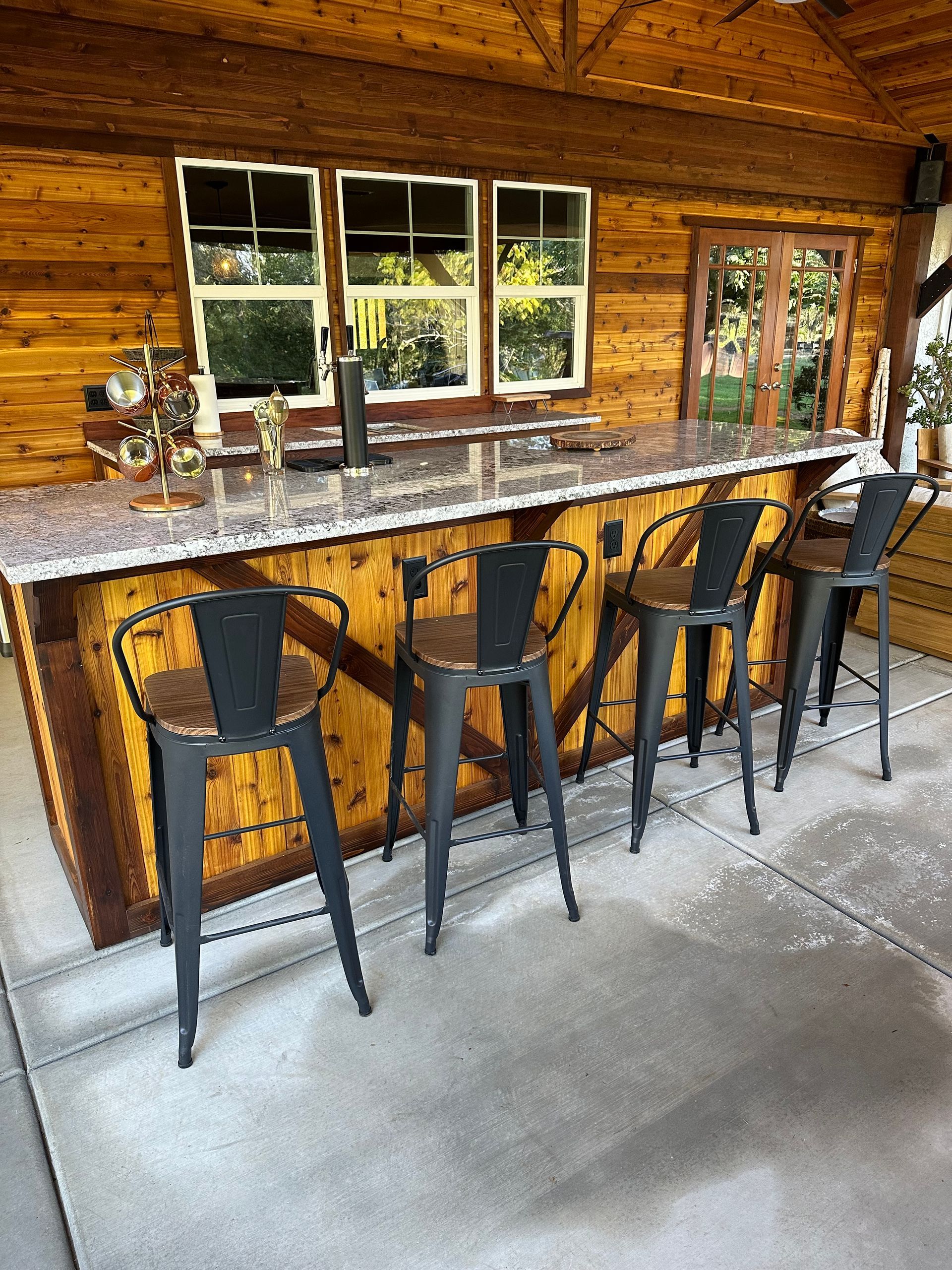 A kitchen with a bar and stools in front of a wooden wall.