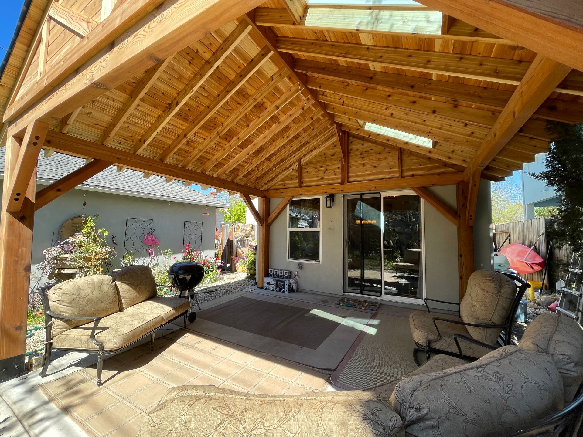 A wooden pavilion with a couch and chairs underneath it.