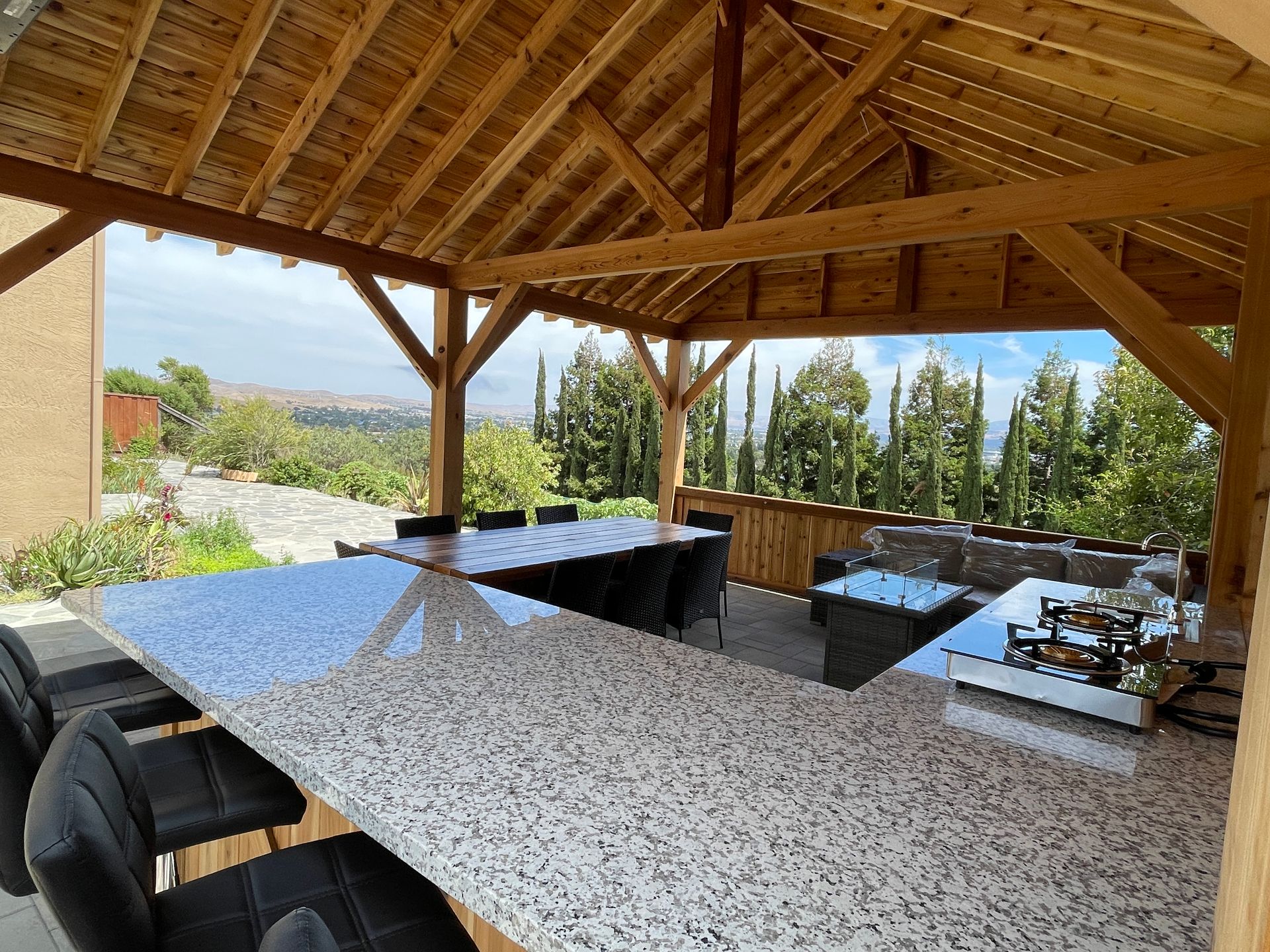 A pavilion with a table and chairs under a wooden roof.