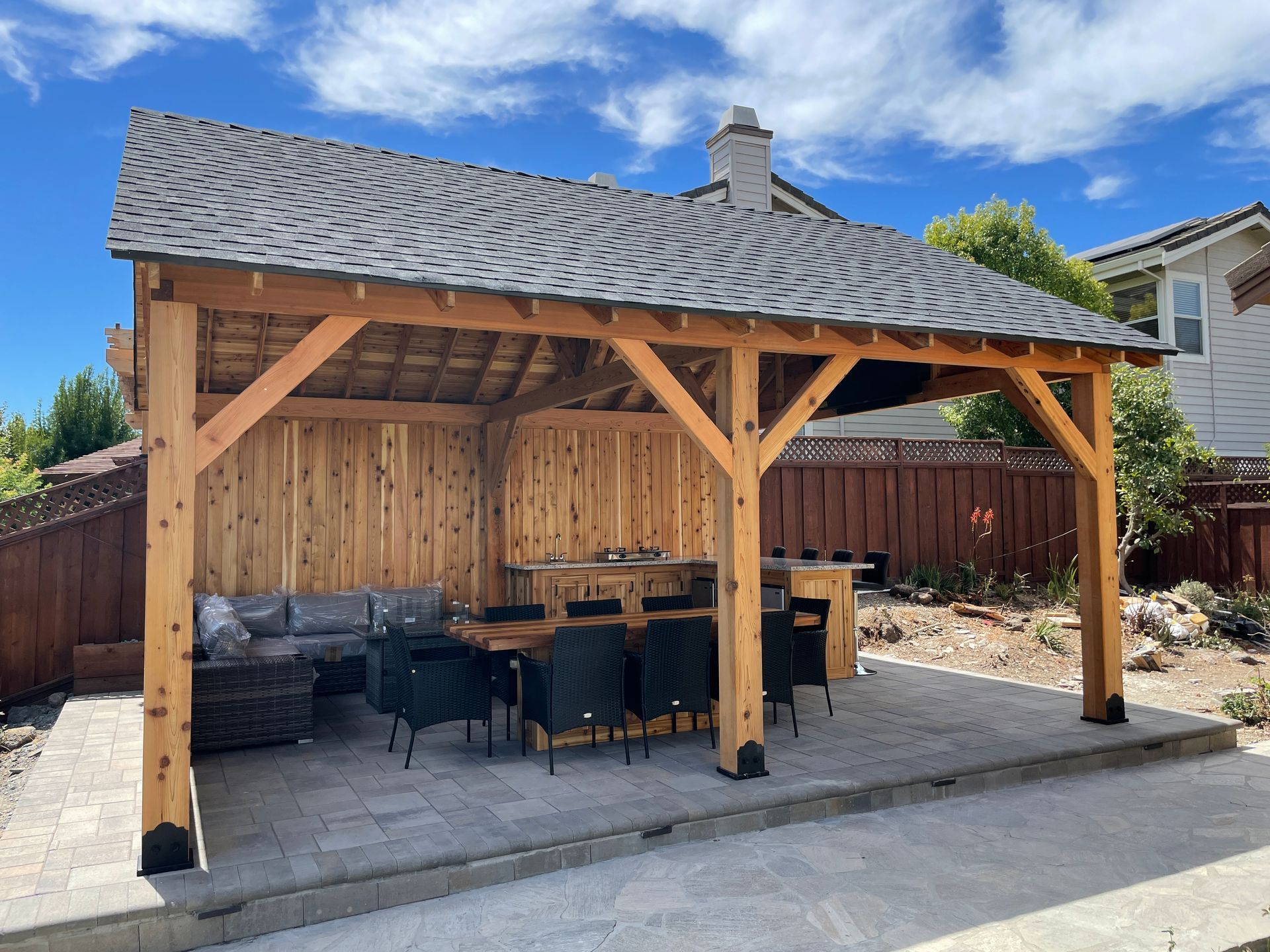 A wooden pavilion with a table and chairs underneath it.