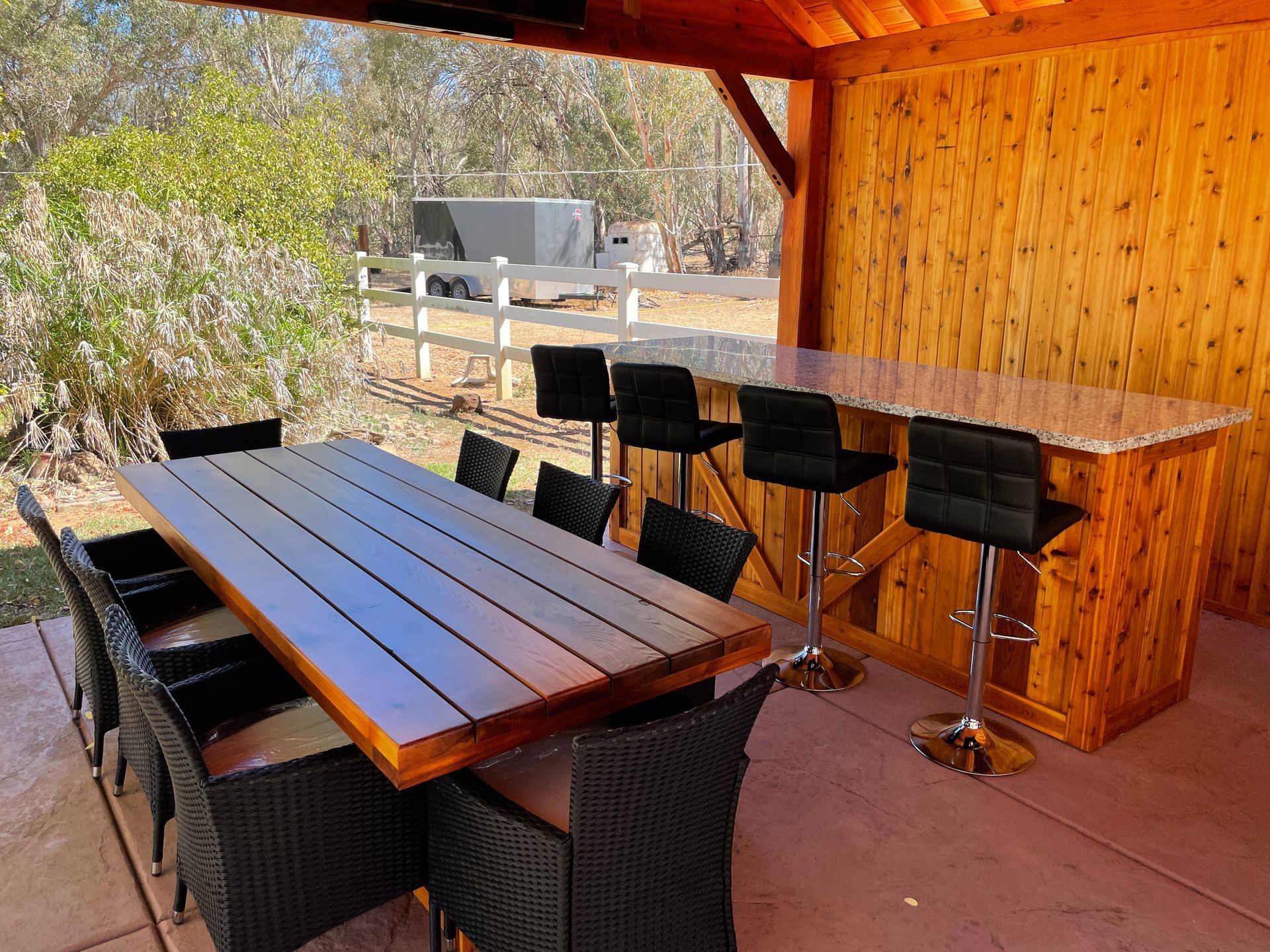 A wooden table and chairs under a wooden roof