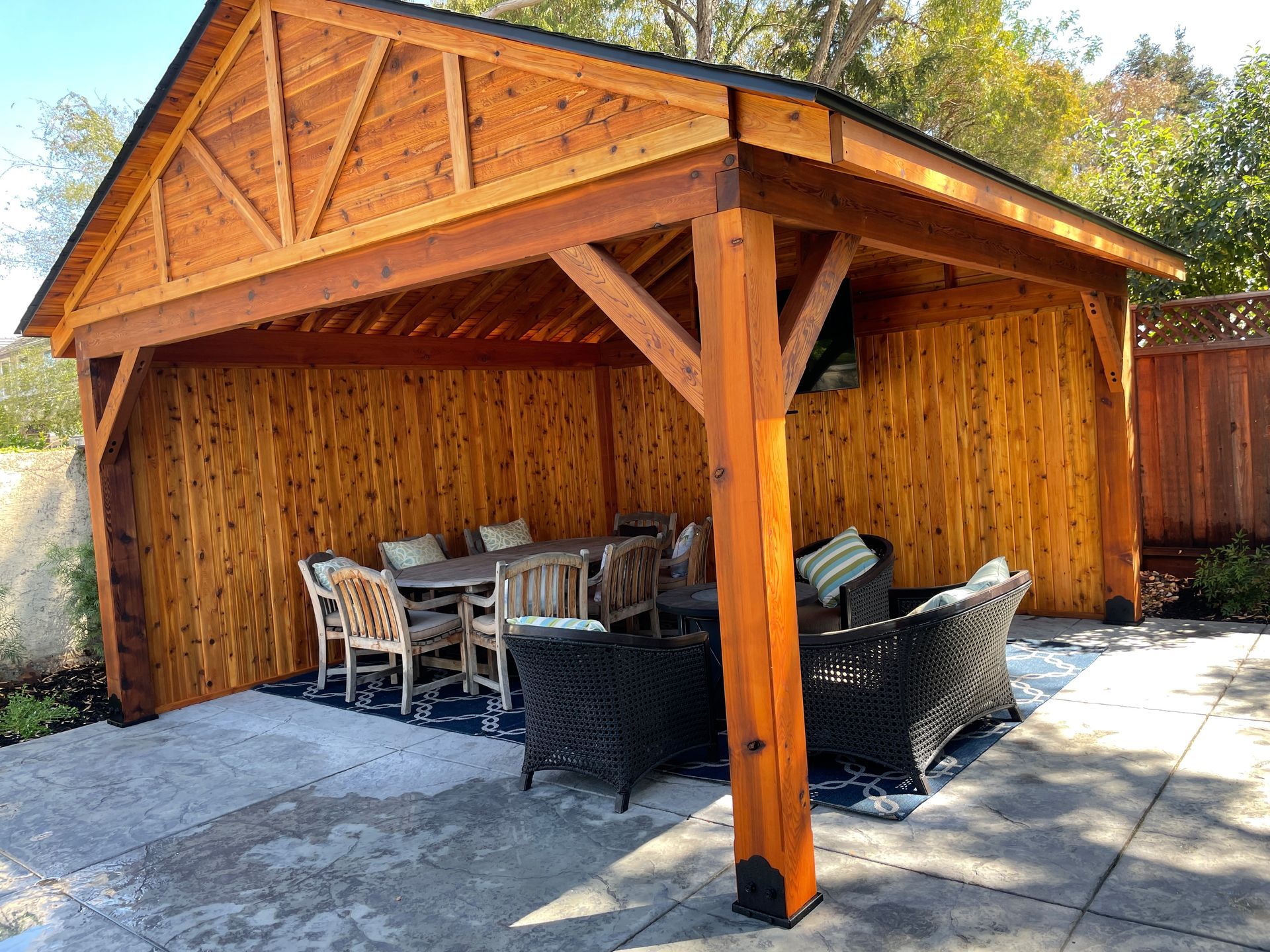 A wooden pavilion with a table and chairs underneath it.