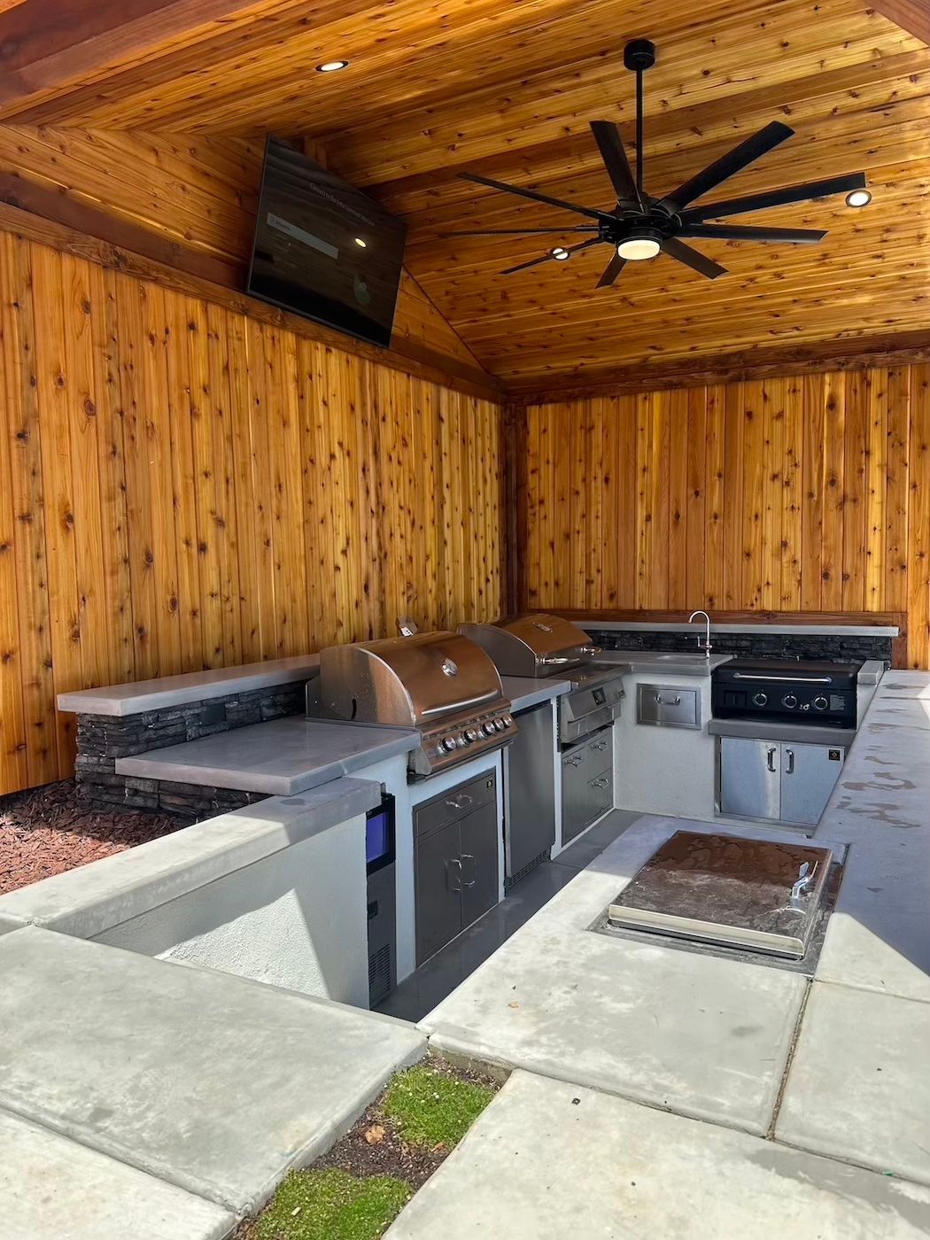 A large outdoor kitchen with a grill and a ceiling fan.