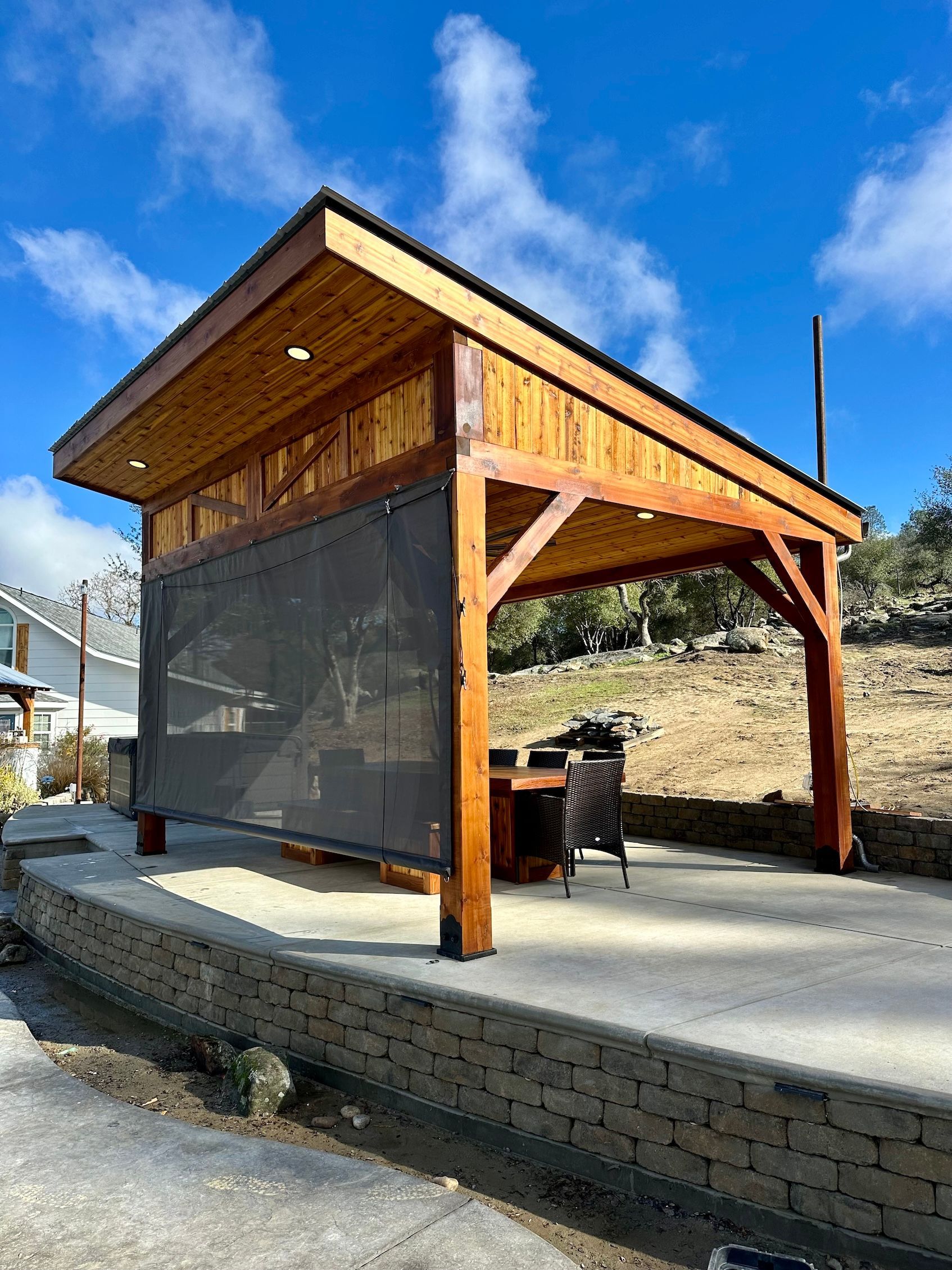 a wooden gazebo with a black screen on the side of it .