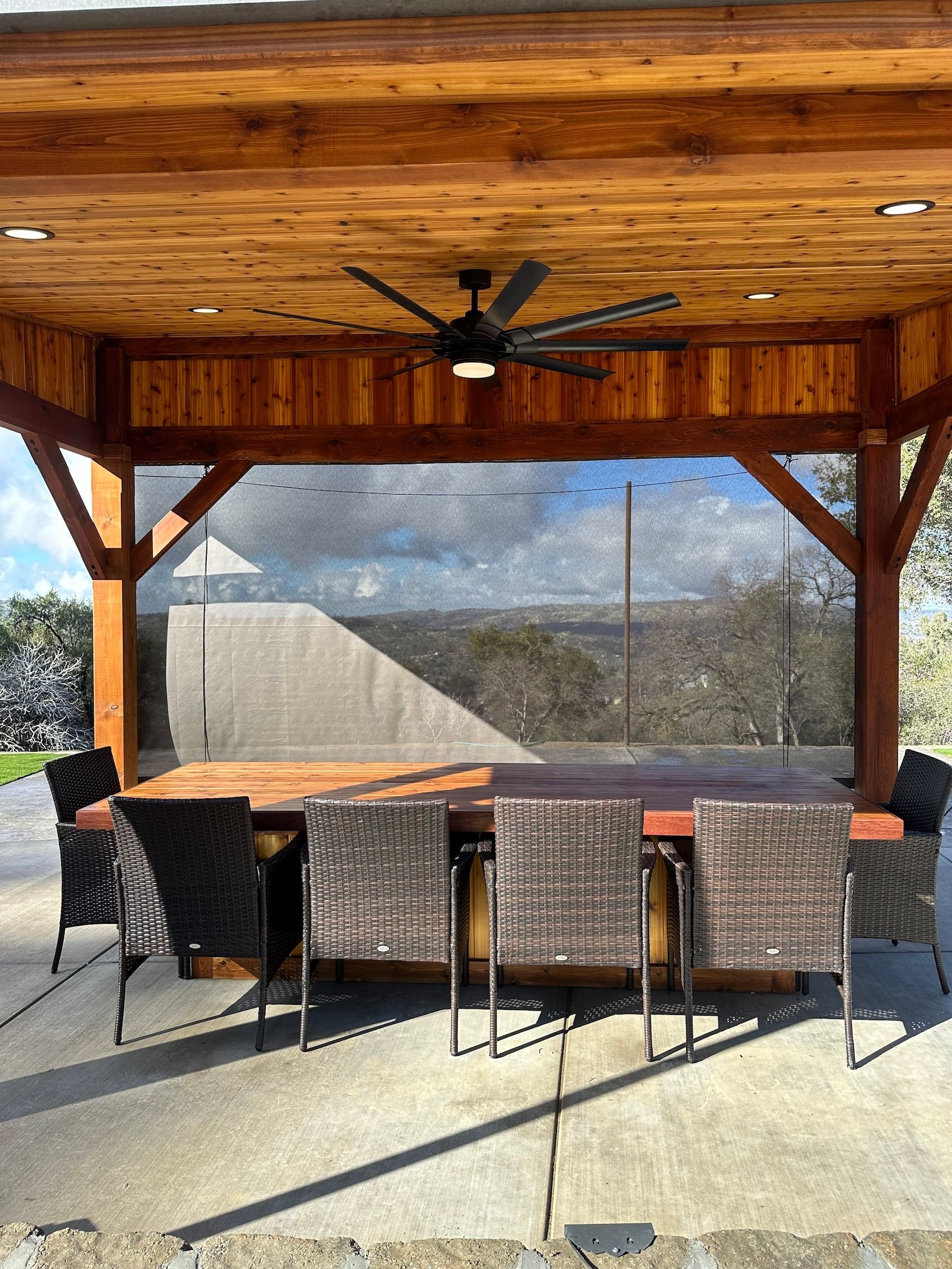 a wooden gazebo with a table and chairs underneath it .