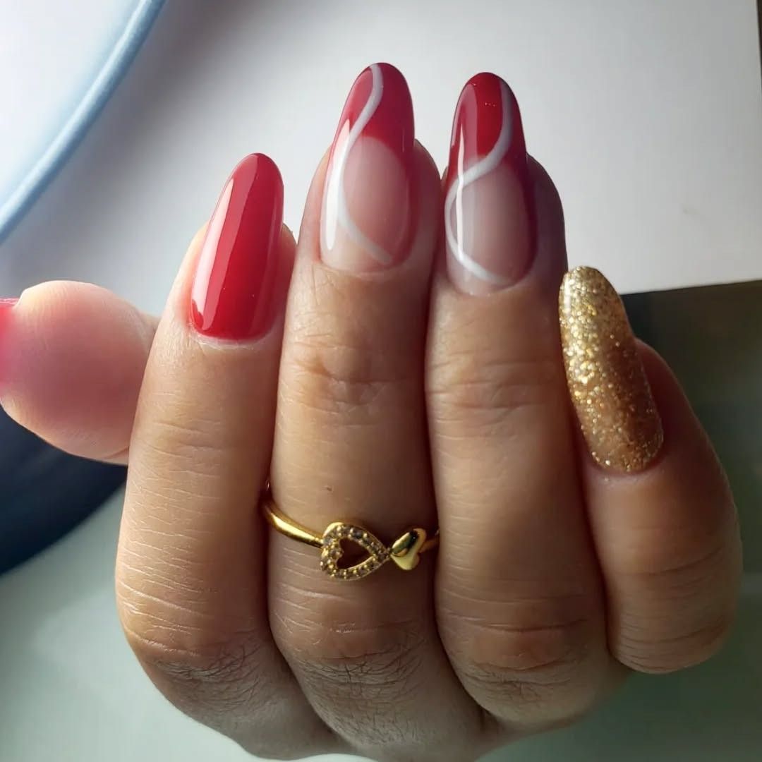 Mano con uñas pintadas de rojo, dorado y punta francesa, luciendo un anillo infinito dorado.