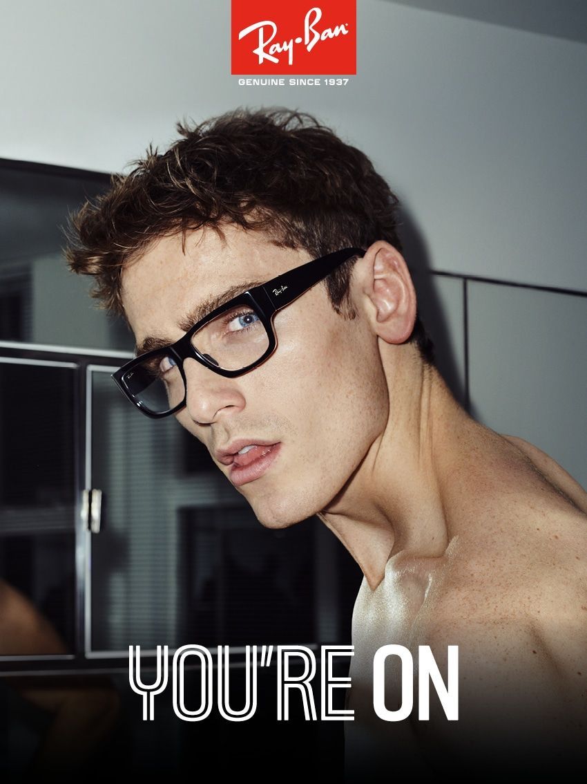 Primo piano di diversi occhiali esposti su una superficie bianca, tra cui un paio ben visibile con montatura blu.