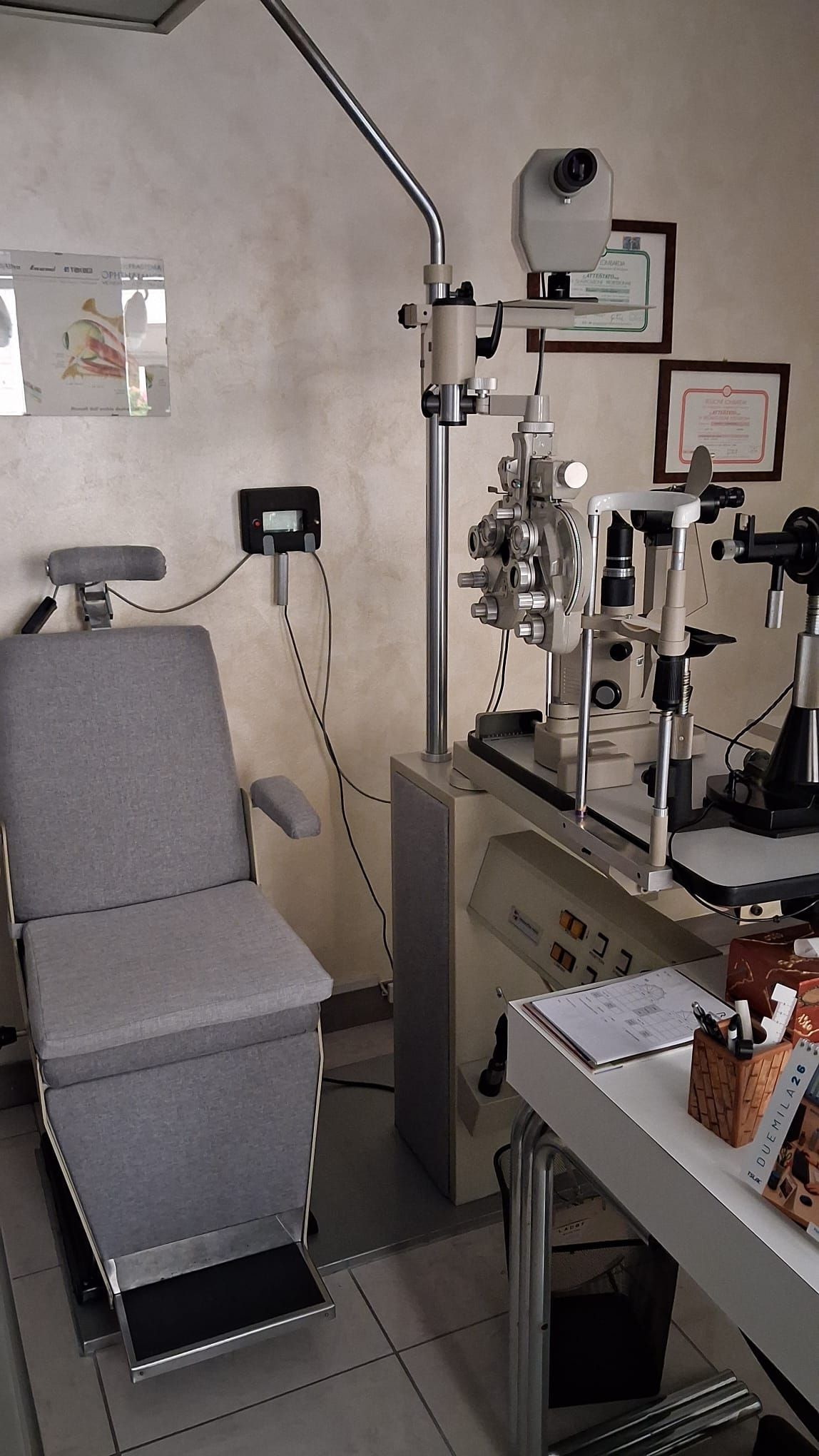 Occhiali da vista esposti, disposti su una parete bianca. Sono visibili montature di vari stili e colori.