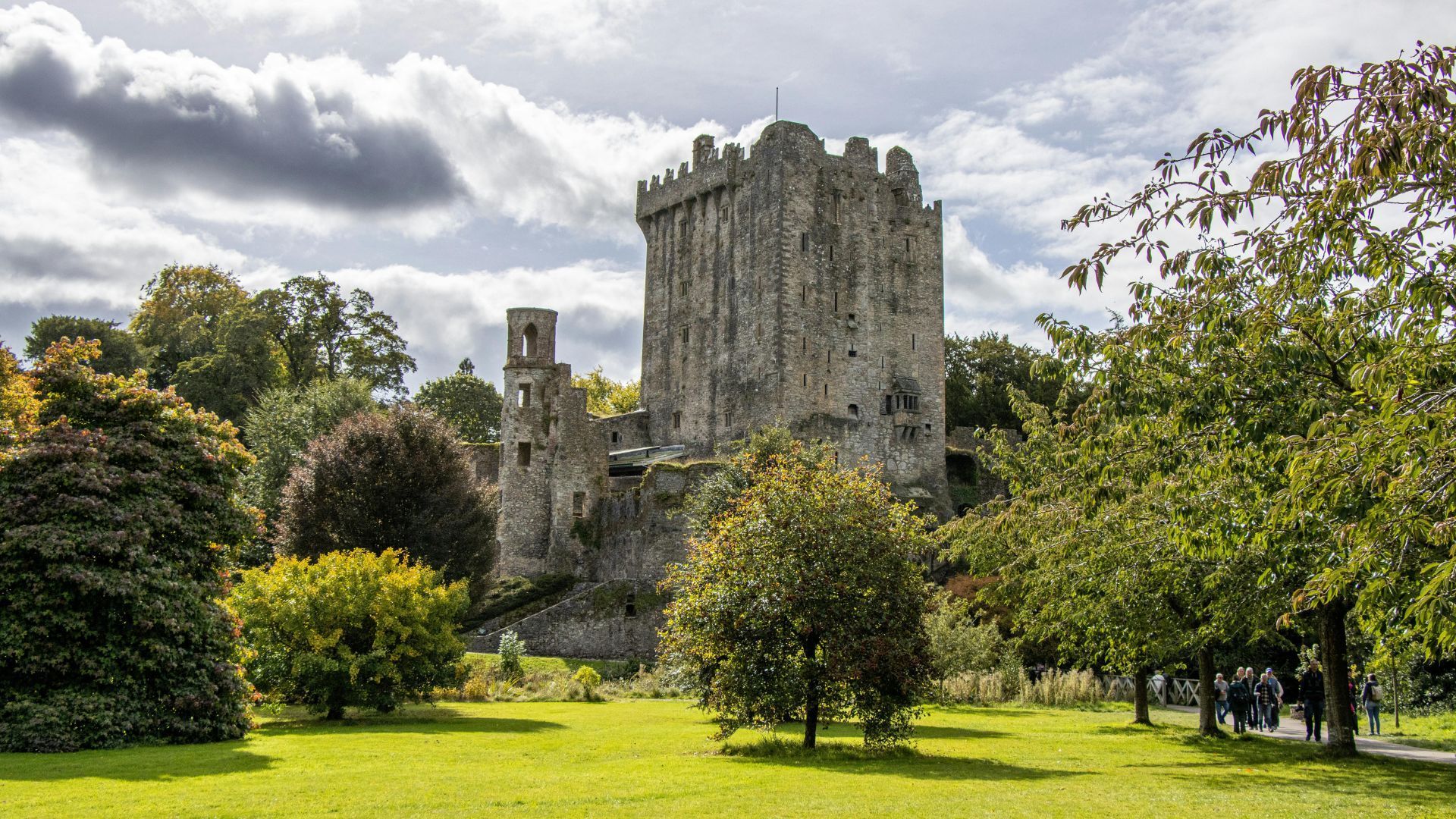 Blarney castle ruins in a green garden under a cloudy sky