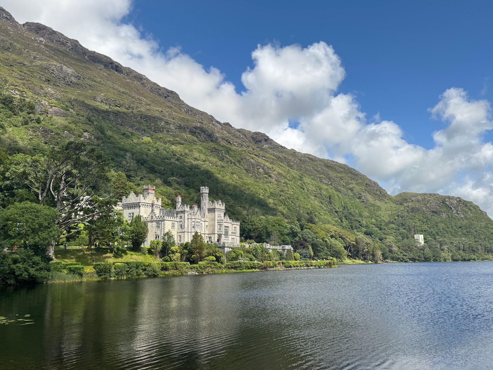 he neo-Gothic facade of Kylemore Abbey reflected in the tranquil waters of Pollacapall Lough, surrounded by the lush mountains of Connemara.