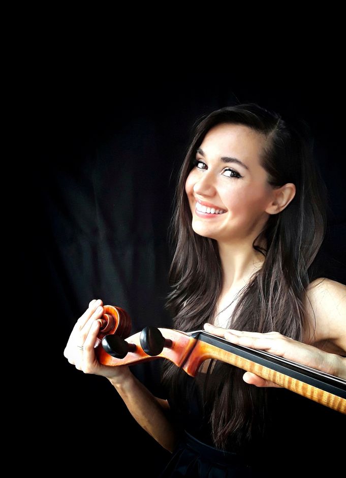 A woman is smiling while holding a violin in her hands