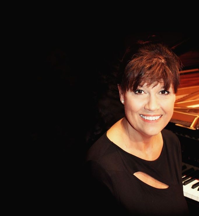 A woman is smiling while sitting at a piano