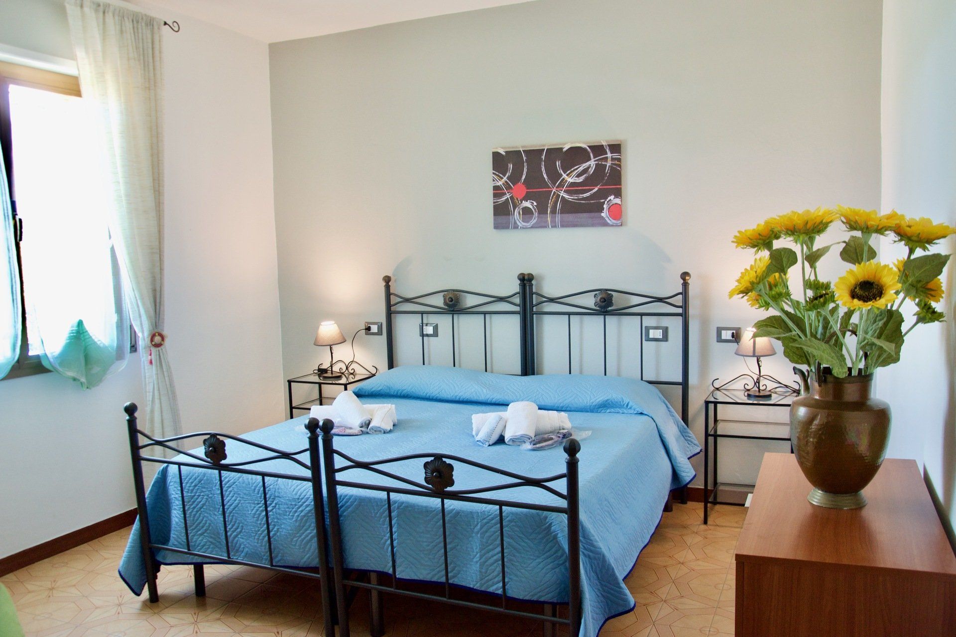 Una camera da letto con un letto e un vaso di girasoli