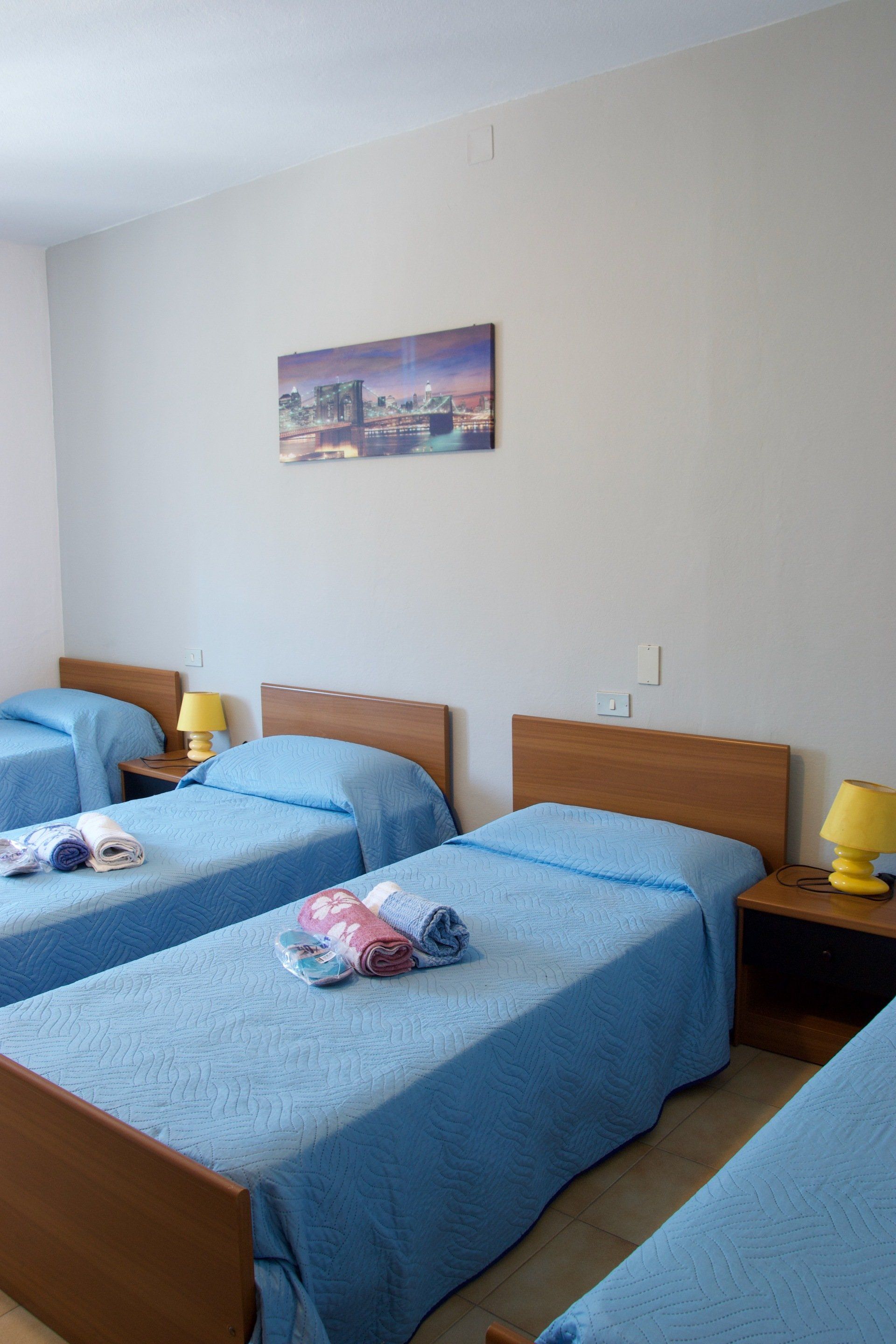 Una camera con tre letti e un quadro alla parete in un hotel con cucina a Bologna