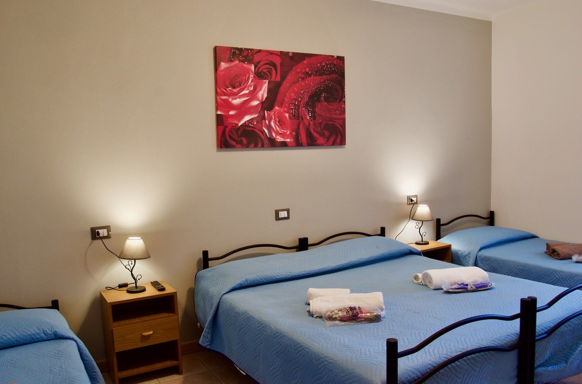 Una camera da letto con tre letti e un dipinto sul muro in un albergo con ristorante nella zona di Bologna