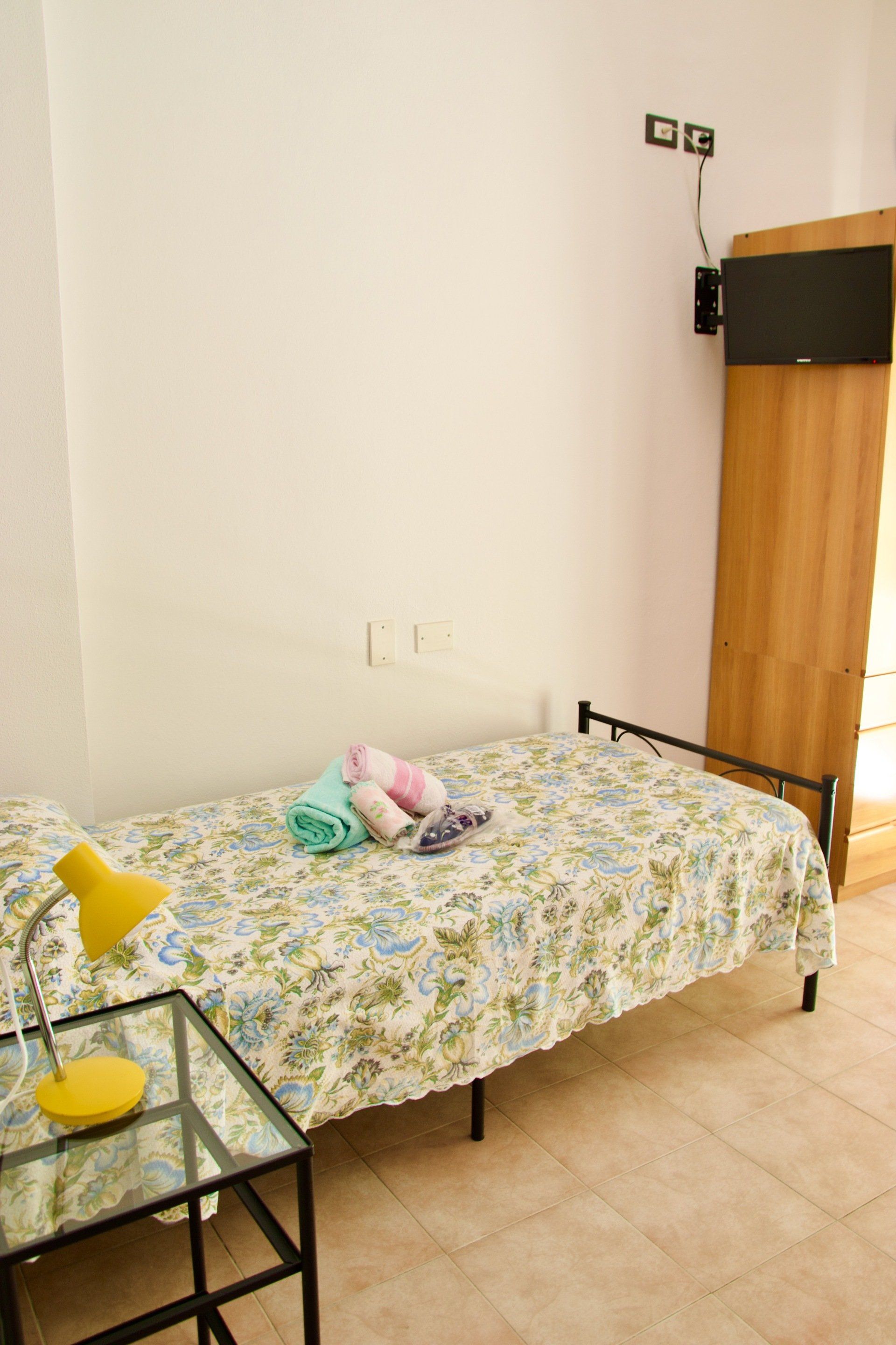 Una camera da letto con un letto singolo, una lampada e una televisione in un hotel con ristorante a Bologna