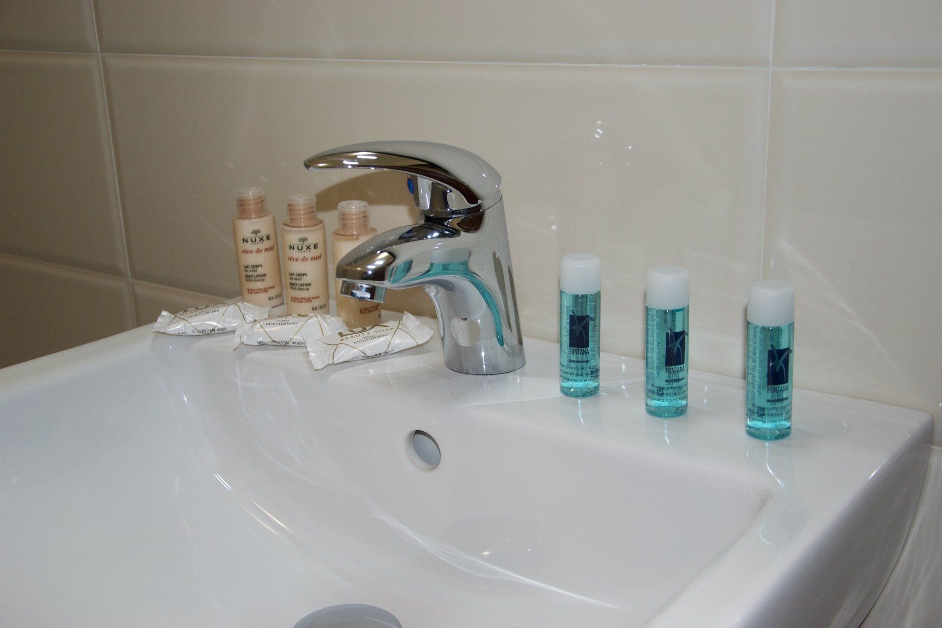 Un lavandino del bagno con tre bottiglie di shampoo sopra in un hotel ristorante a Bologna