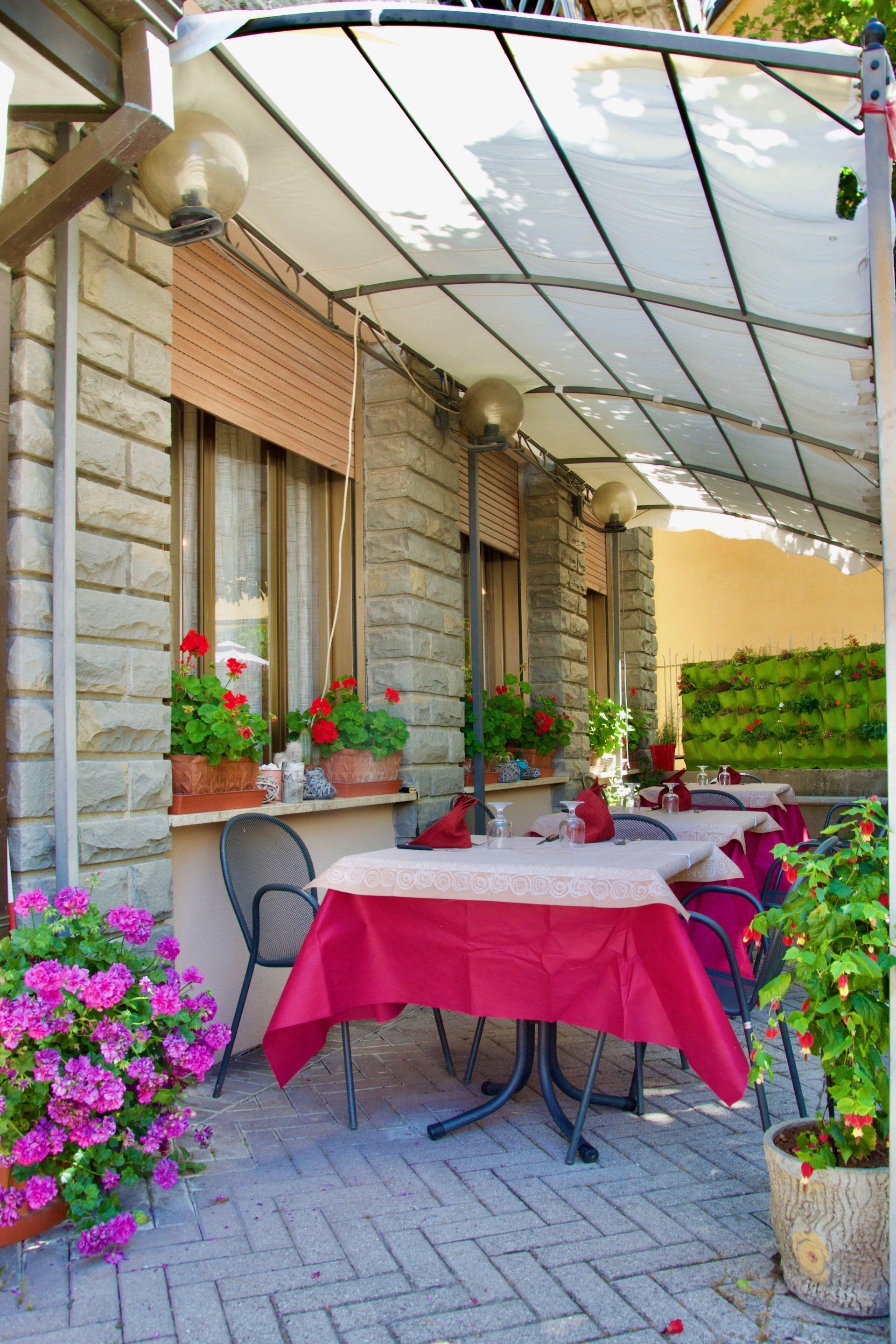 Un patio con tavoli e sedie sotto una tenda da sole nel ristorante con piatti di funghi e tartufo a Bologna