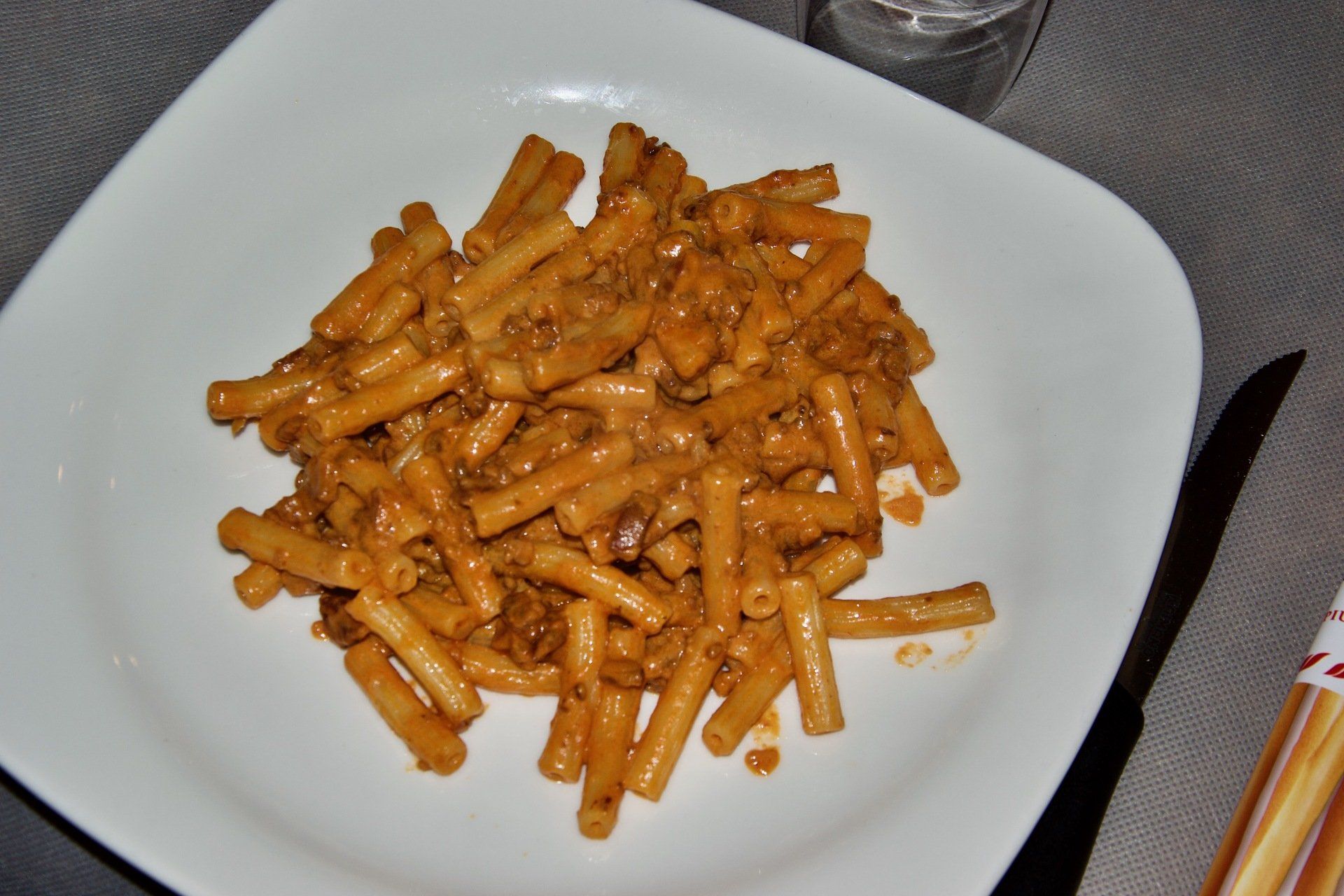 Un piatto bianco con sopra maccheroni e formaggio su un tavolo