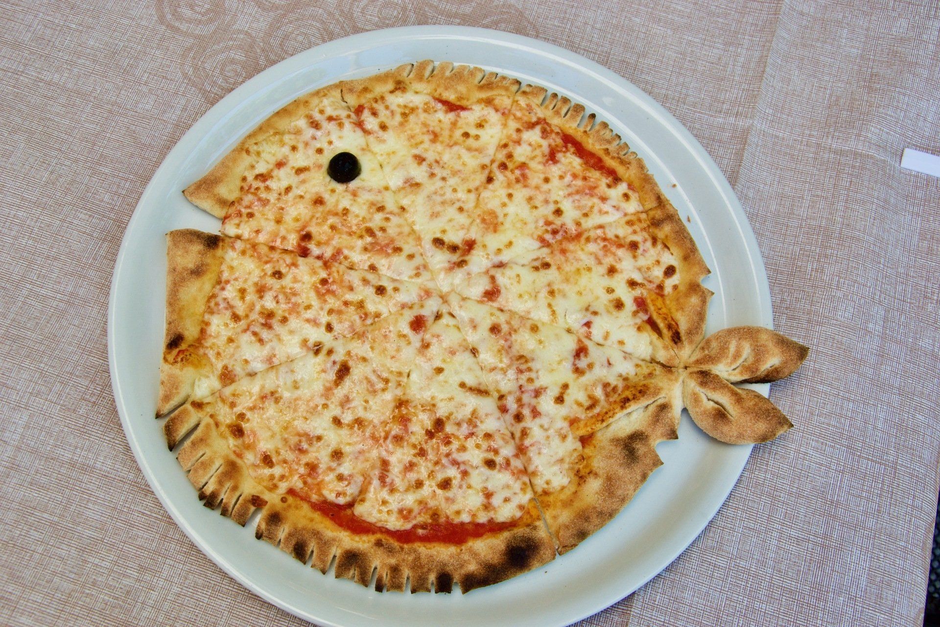 Una pizza a forma di pesce su un piatto bianco