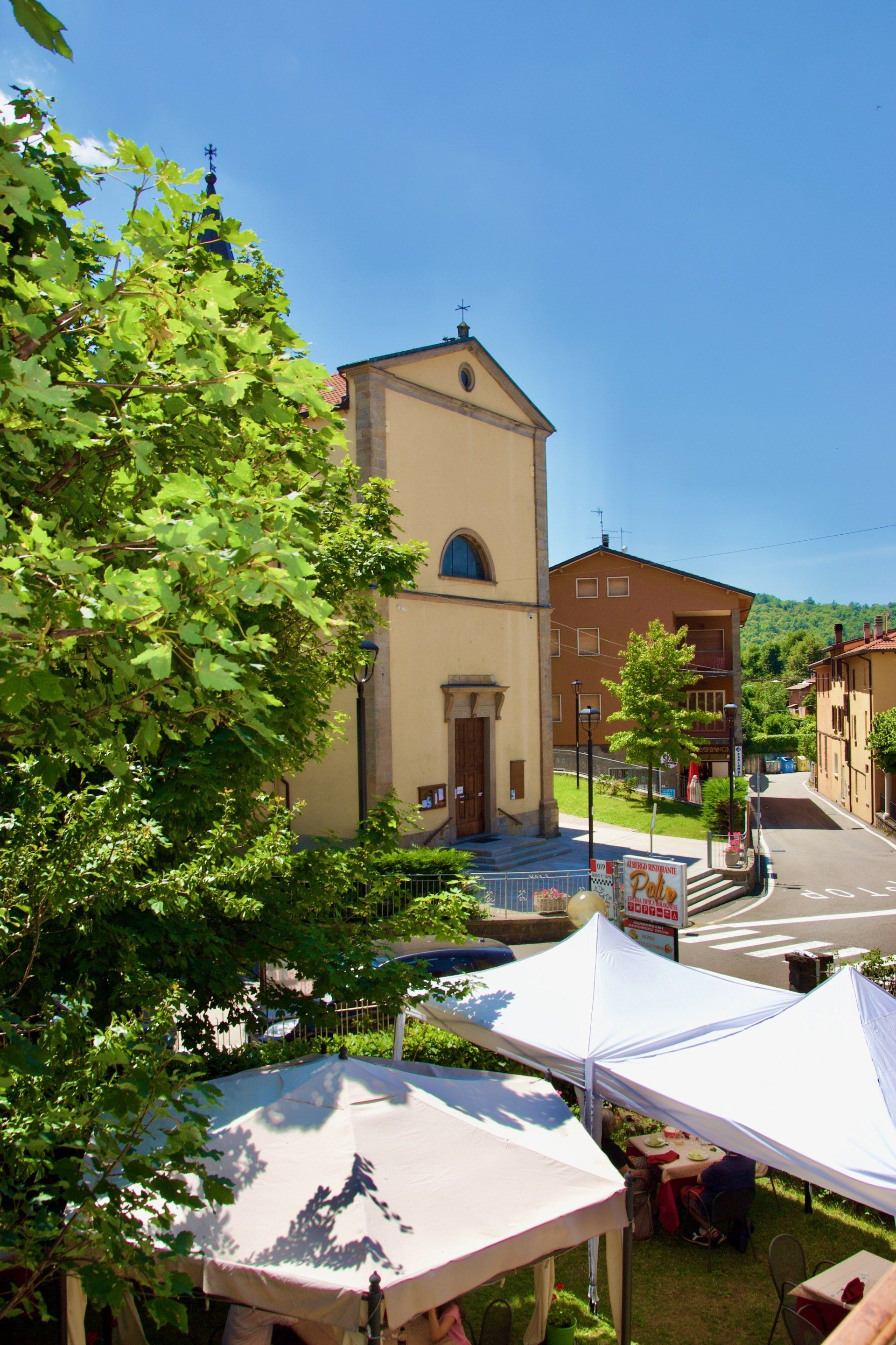 Una chiesa è circondata da tende e alberi in una piccola cittadina.