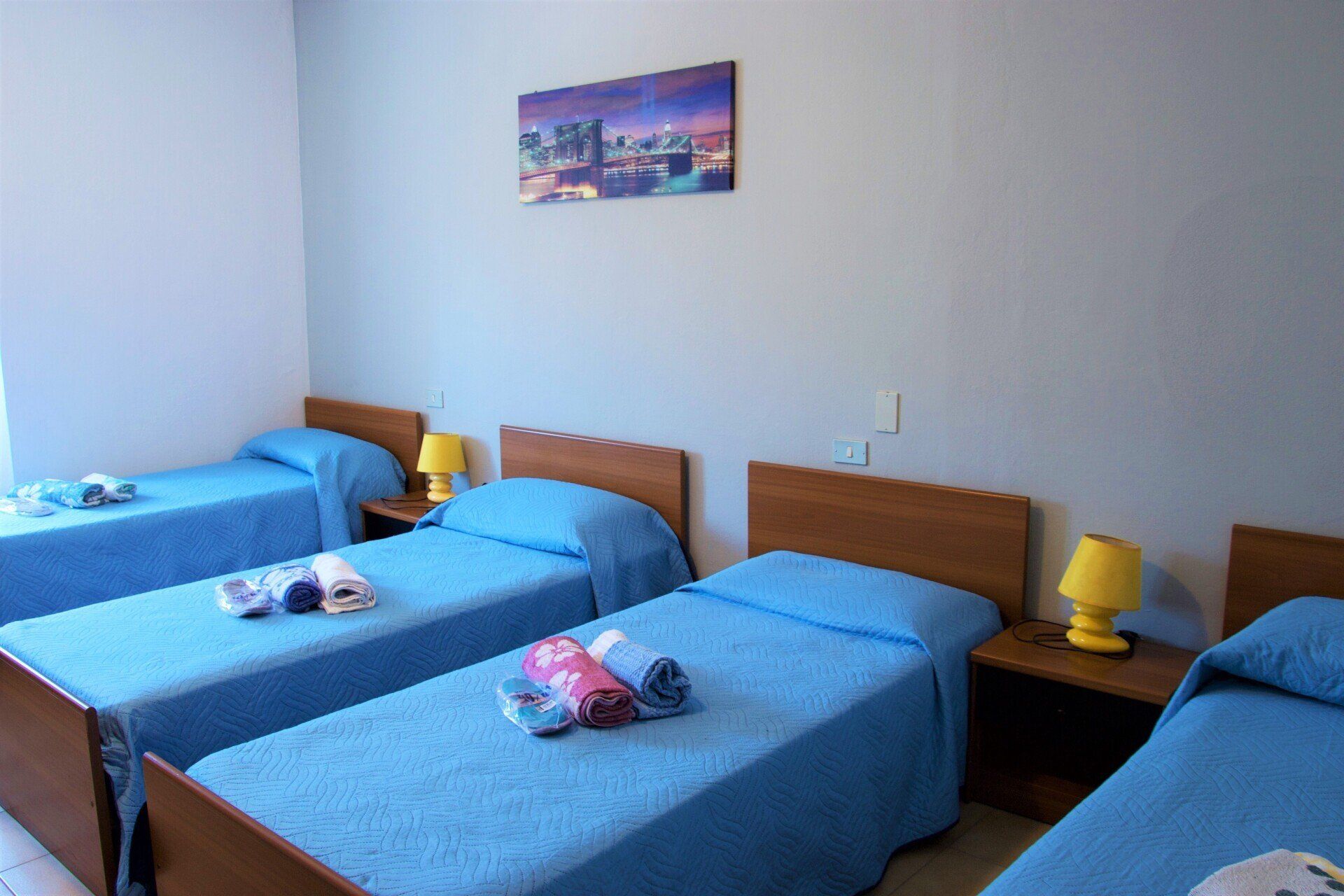 Una camera da letto con tre letti e un dipinto sul muro in un albergo con ristorante a Bologna