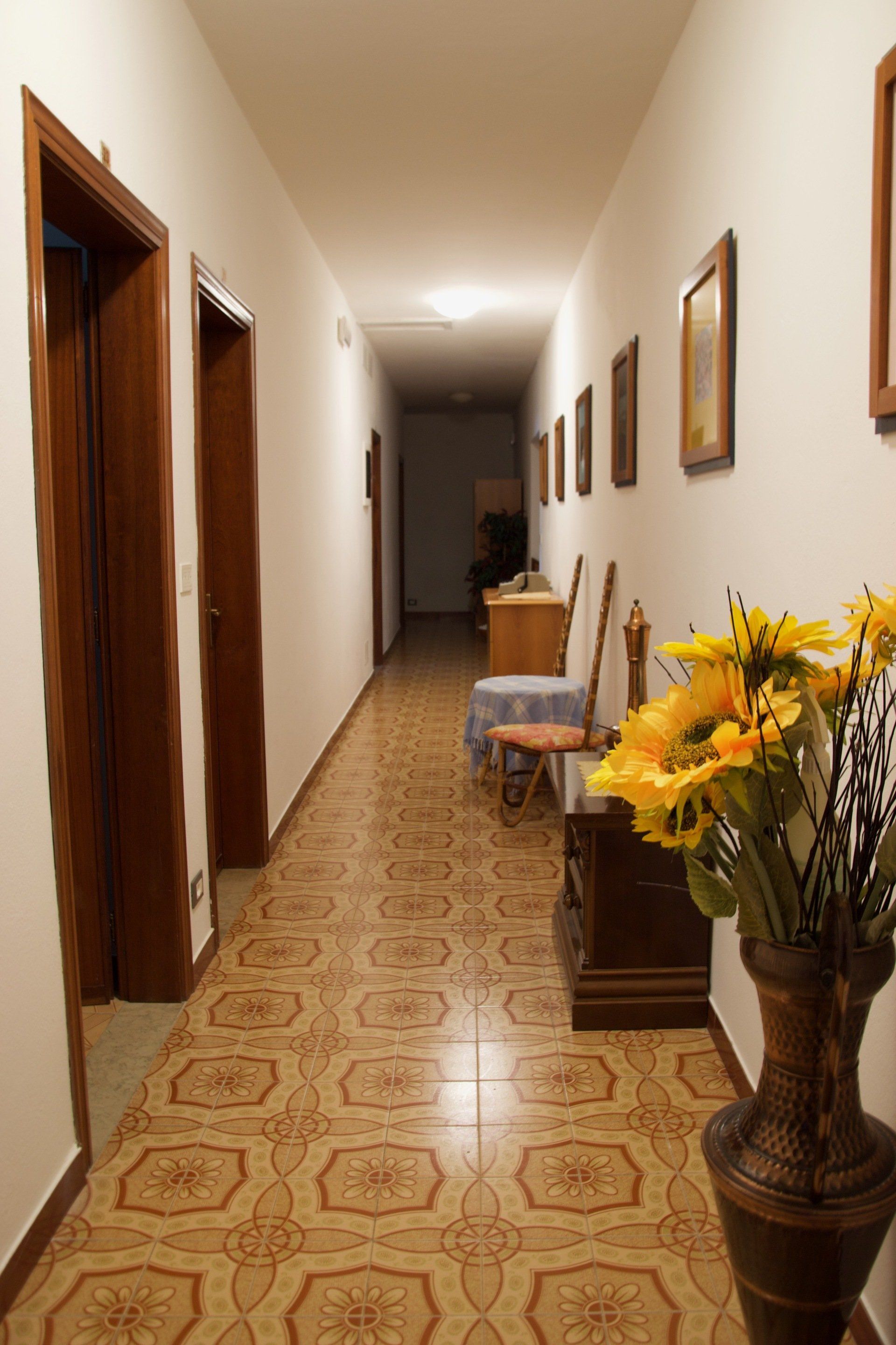 Un lungo corridoio con un vaso di fiori sul pavimento