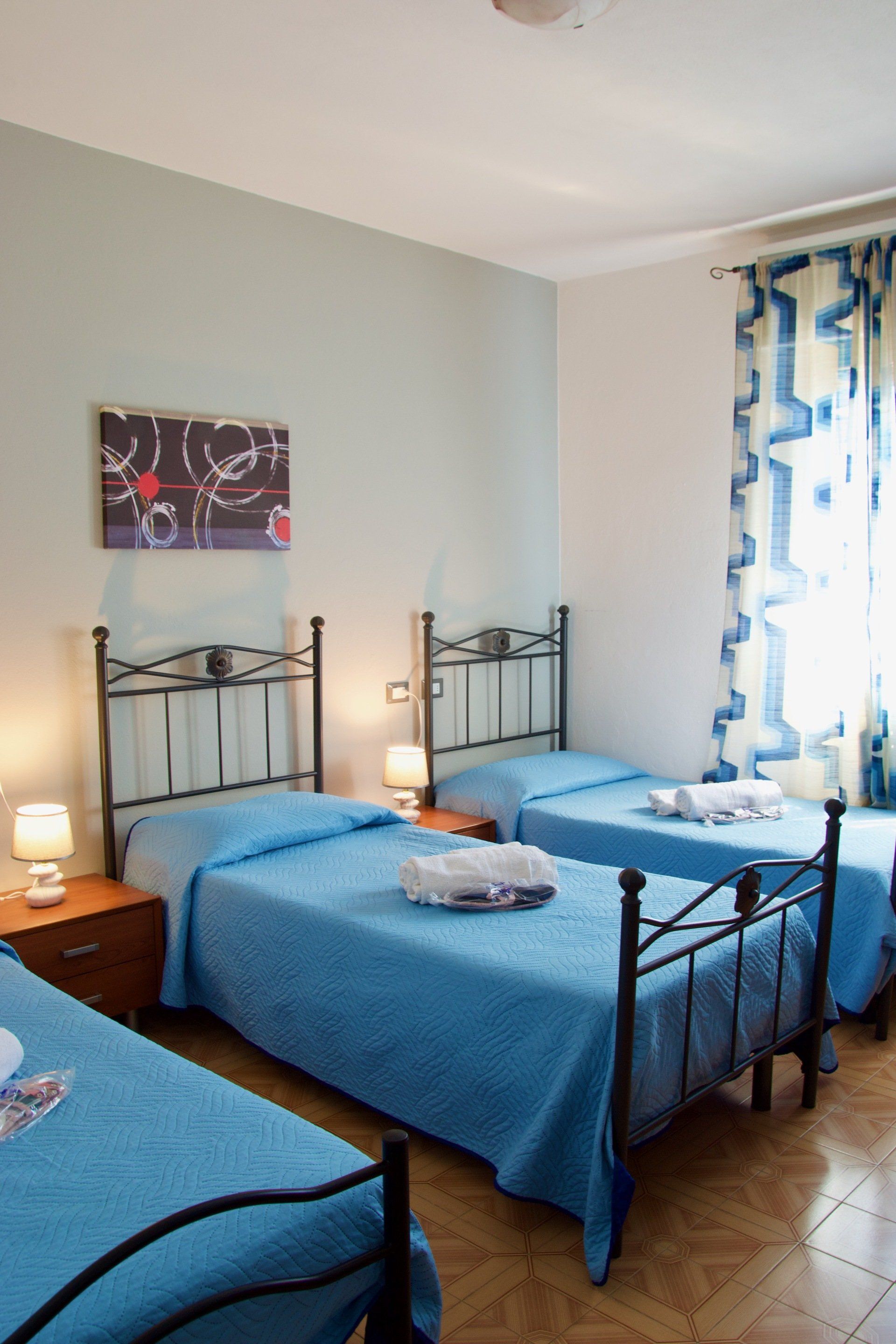 Una camera da letto con tre letti e un dipinto sul muro