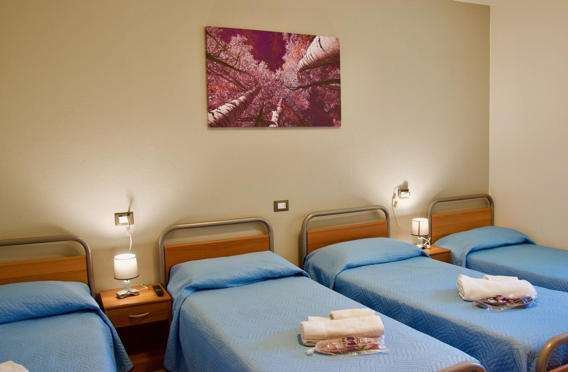 Una camera da letto con tre letti e un dipinto sul muro