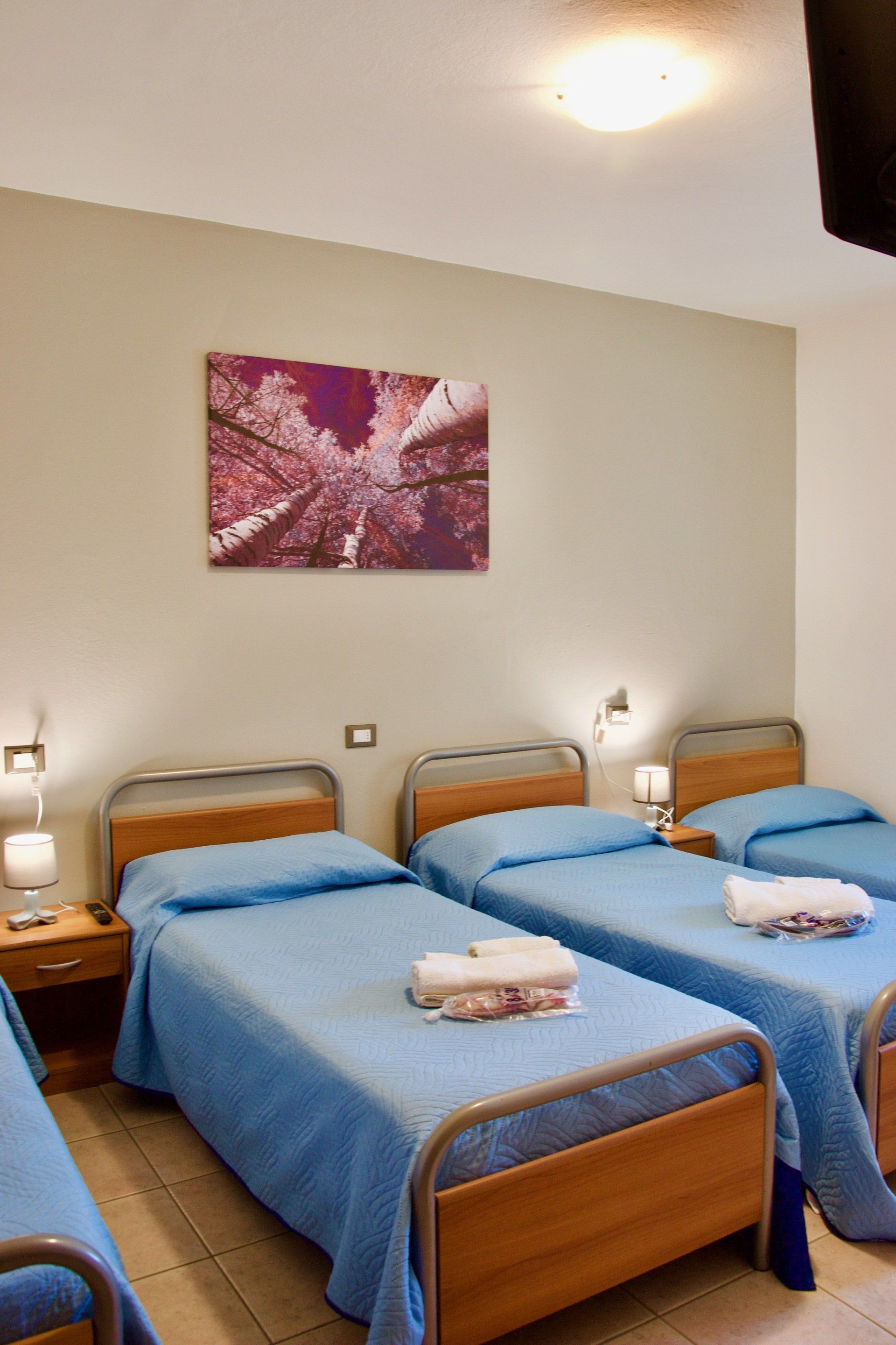 Una camera d'albergo con tre letti e un dipinto sul muro