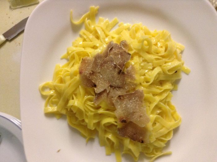 Un piatto bianco con sopra tagliatelle e carne su un tavolo.