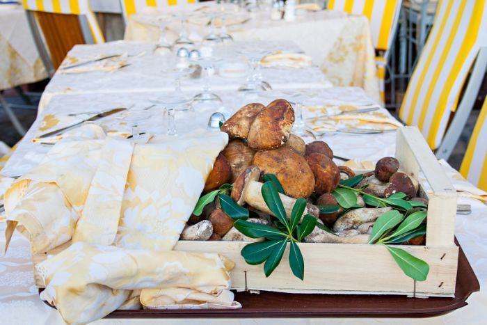 Una scatola di legno piena di funghi e foglie su un tavolo.