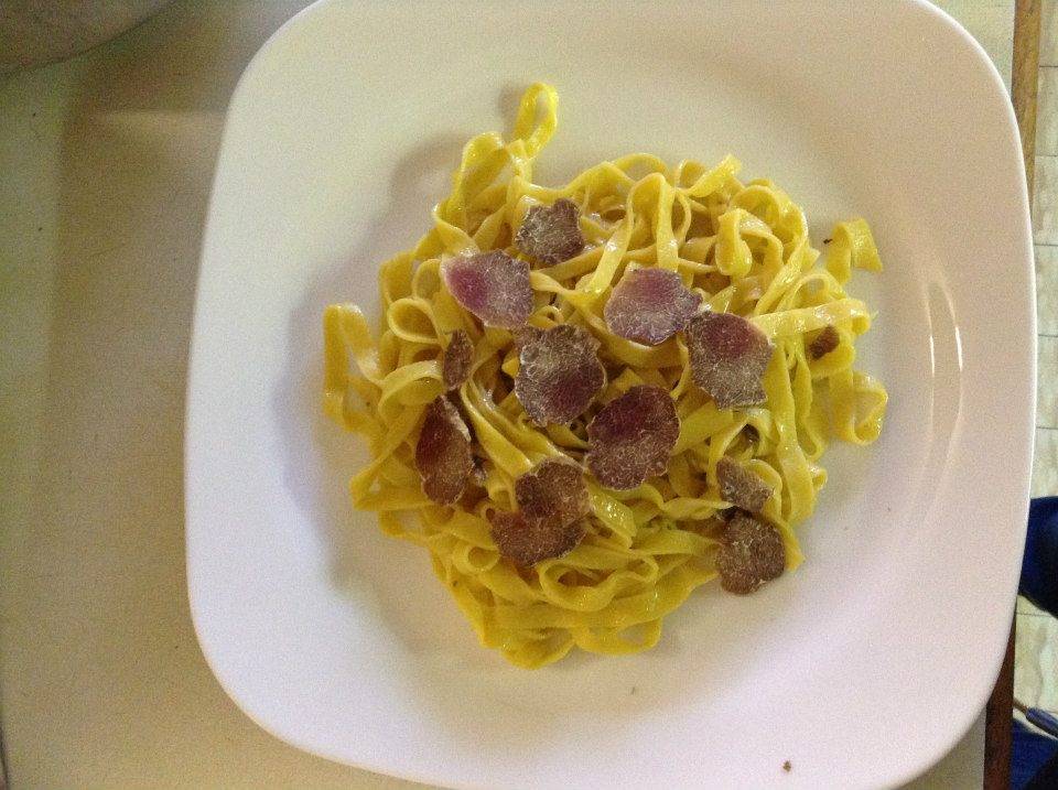 Un piatto bianco con sopra tagliatelle e carne su un tavolo