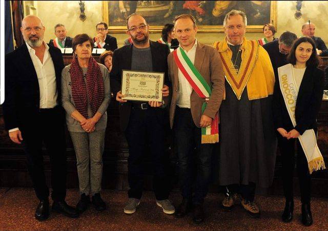 Un gruppo di persone in posa per una foto con un uomo che tiene in mano un certificato